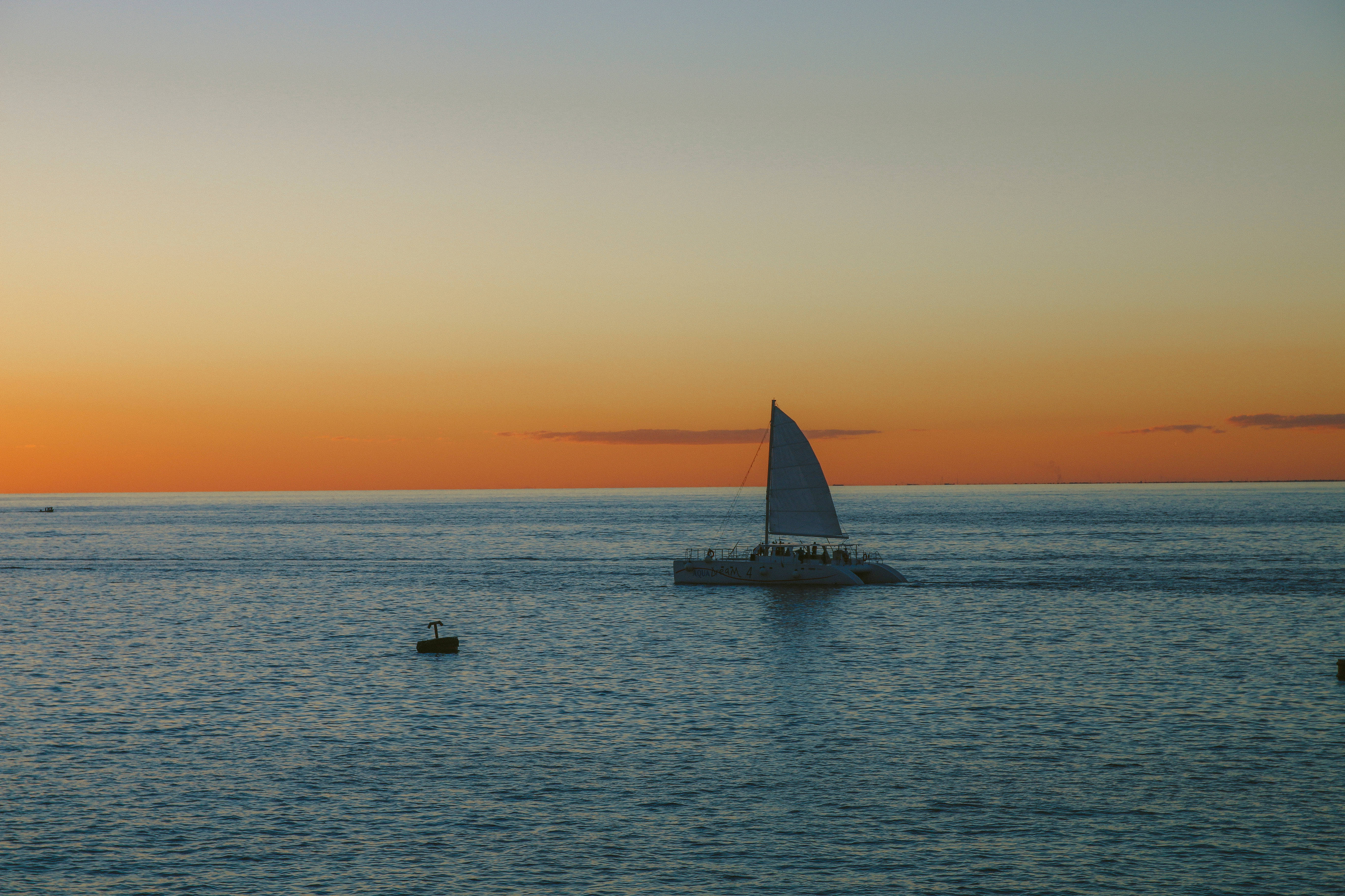 sailing catamaran, calm ocean waters, vibrant orange and blue sunset sky, 5K Desktop Wallpaper
