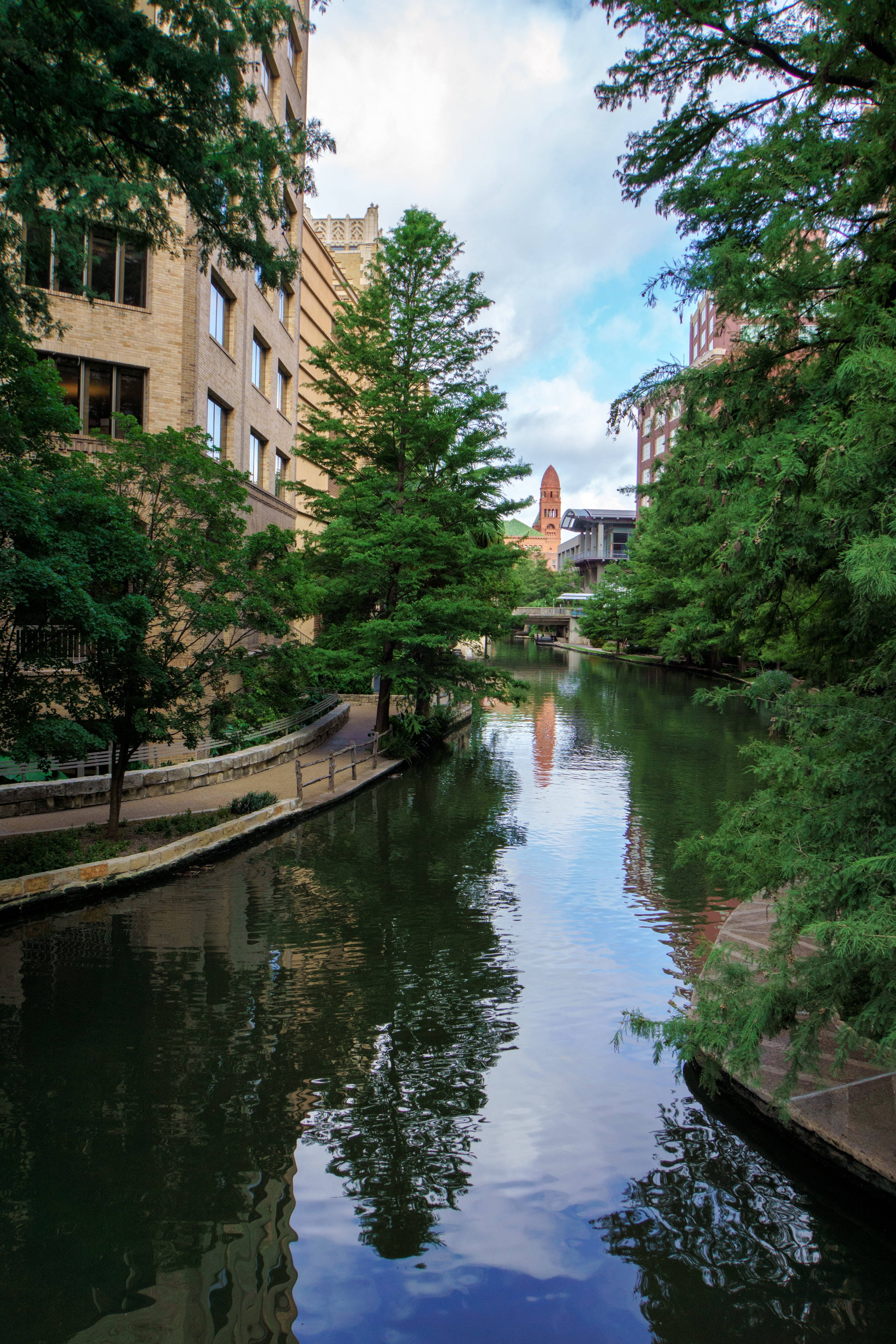 San Antonio River Walk, lush green trees, historic brick buildings, 4K Phone Wallpaper