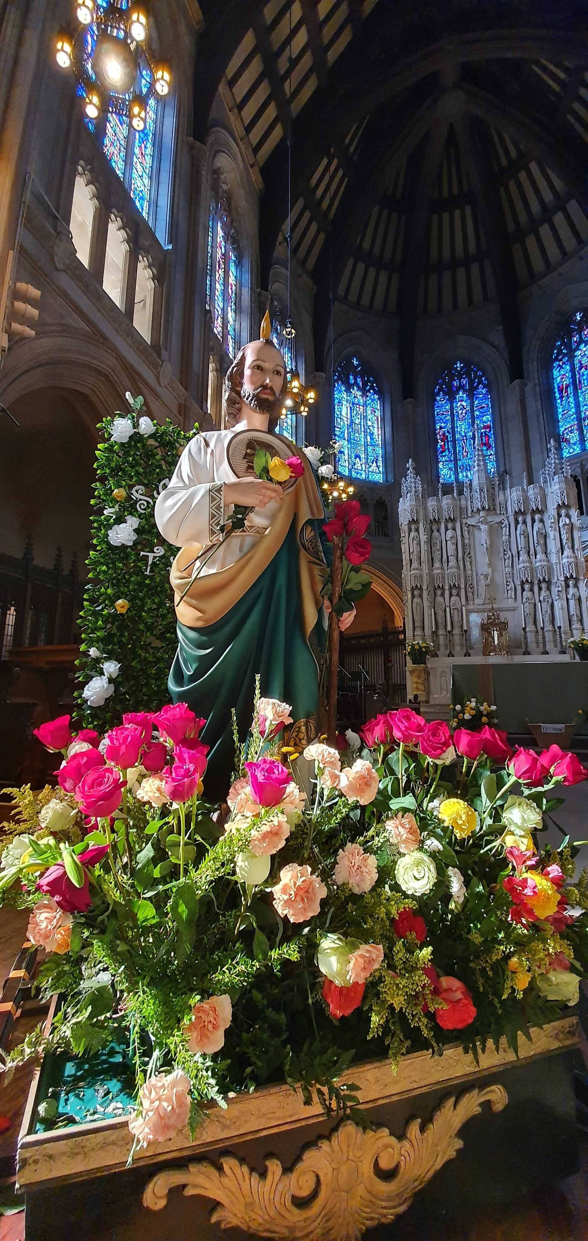 San Judas, statue of Jesus Christ, vibrant pink peach and yellow roses, 4K Phone Wallpaper