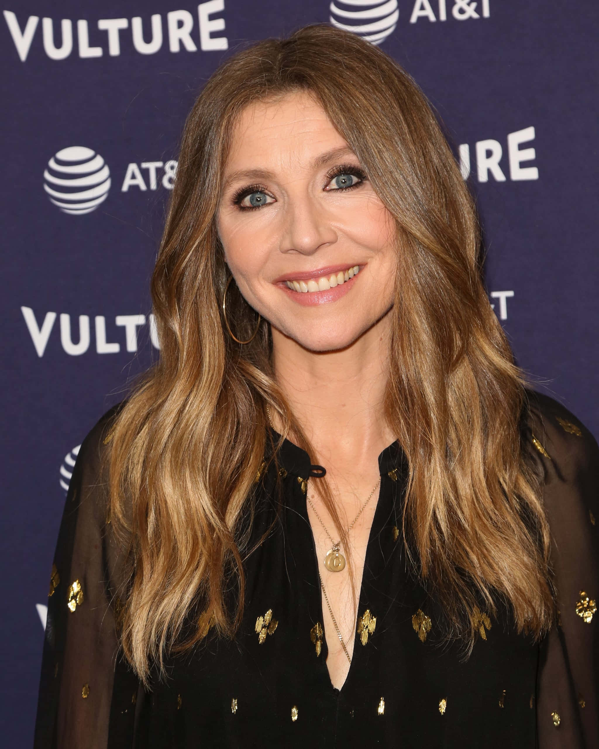 Sarah Chalke, black gold-patterned top, purple branded backdrop, 2K Phone Wallpaper