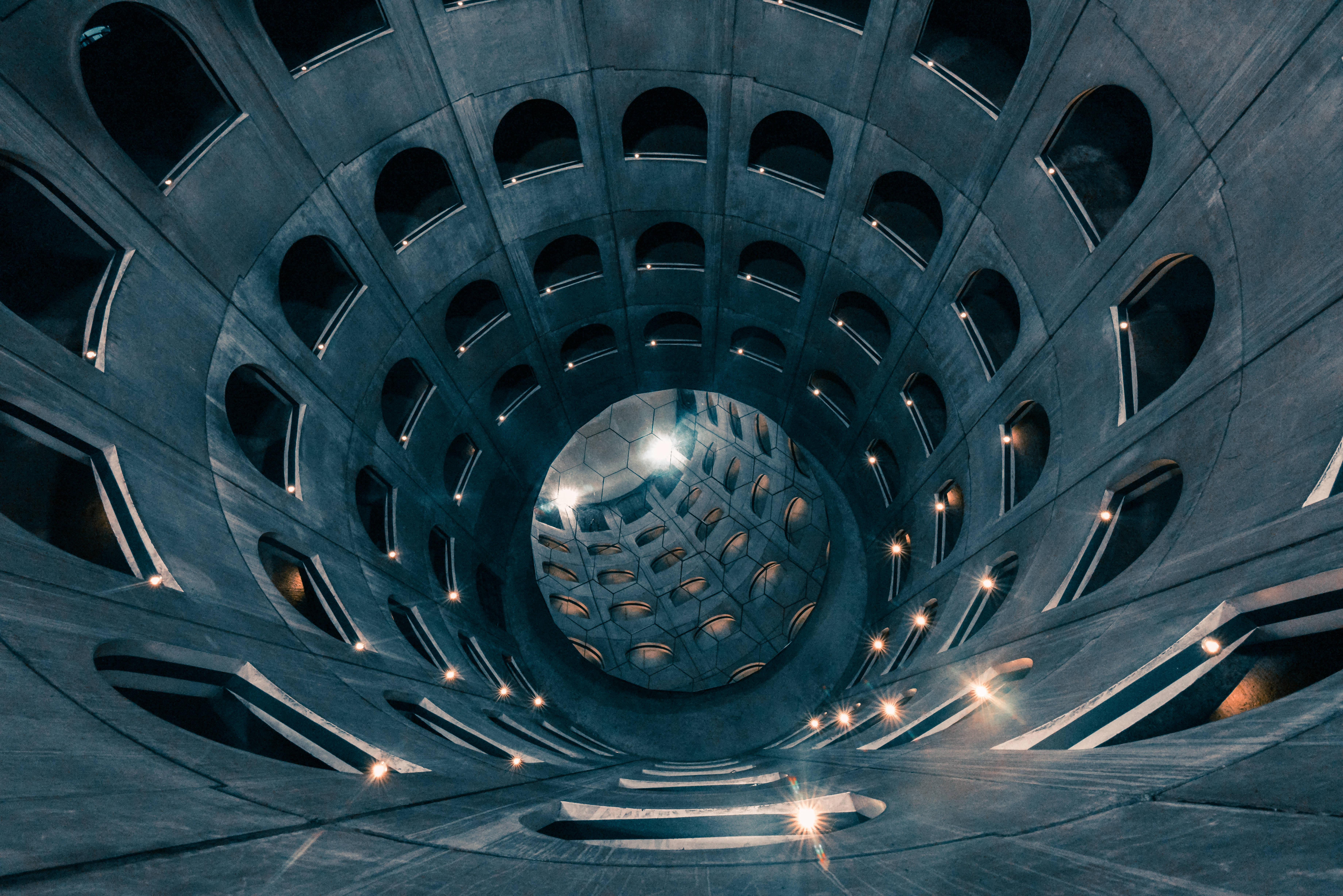 underground car park, spiraling concrete architectural structure, glowing lights, 5K Desktop Wallpaper