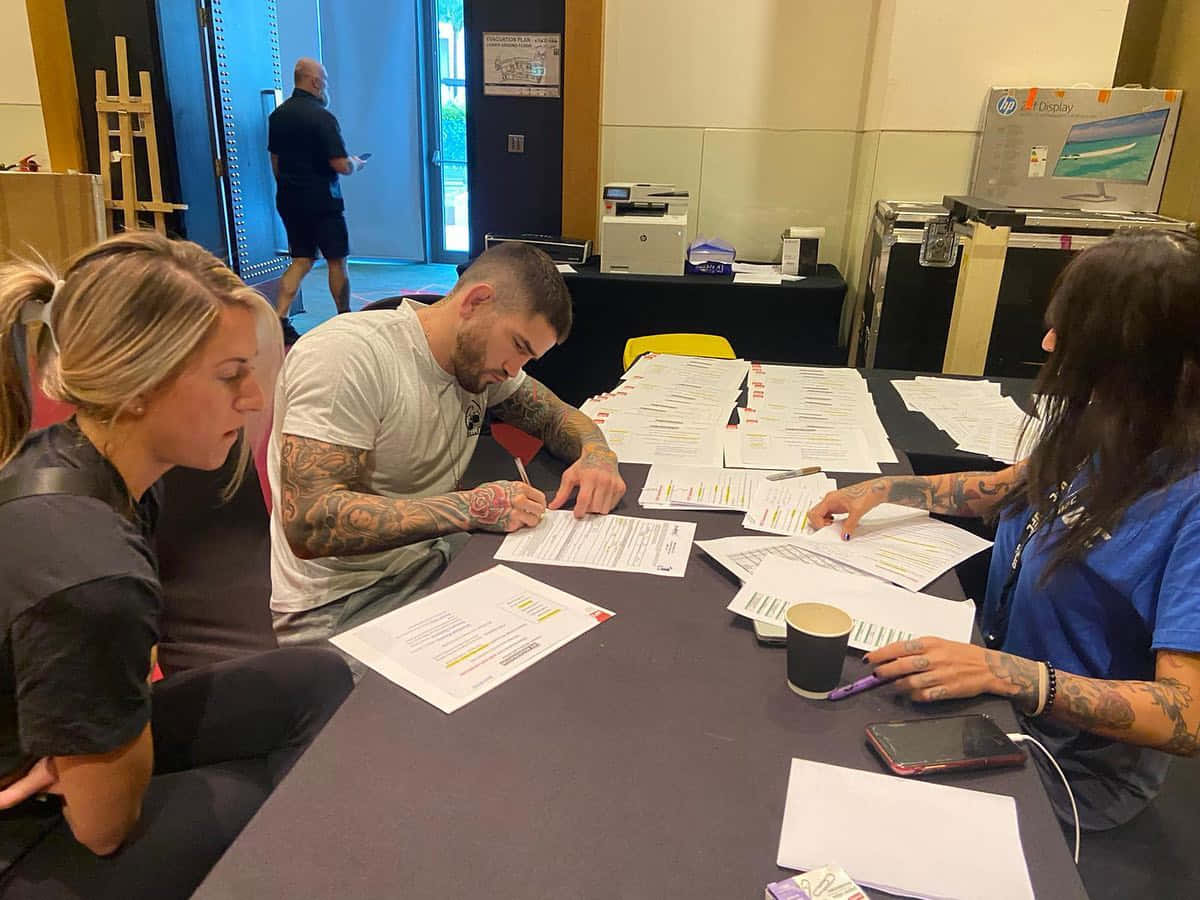 Sean Brady, signing papers, cluttered conference table, SD Desktop Wallpaper