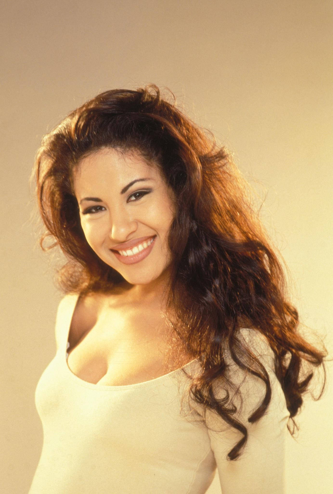 Selena Quintanilla, voluminous brown curls, soft beige studio backdrop, Full HD Phone Wallpaper
