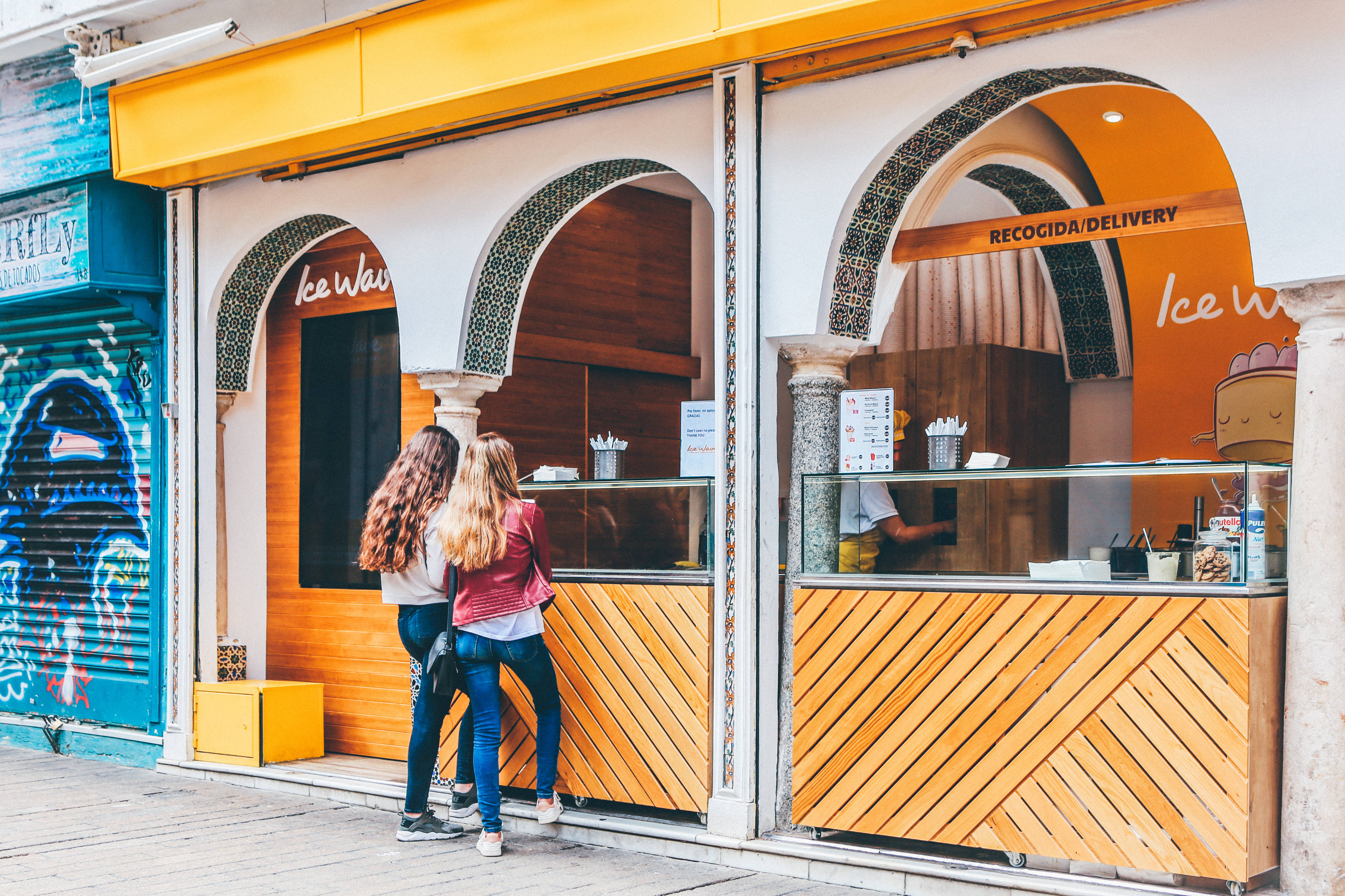 Seville, vibrant orange wooden ice cream kiosk, arched windows, 4K Desktop Wallpaper
