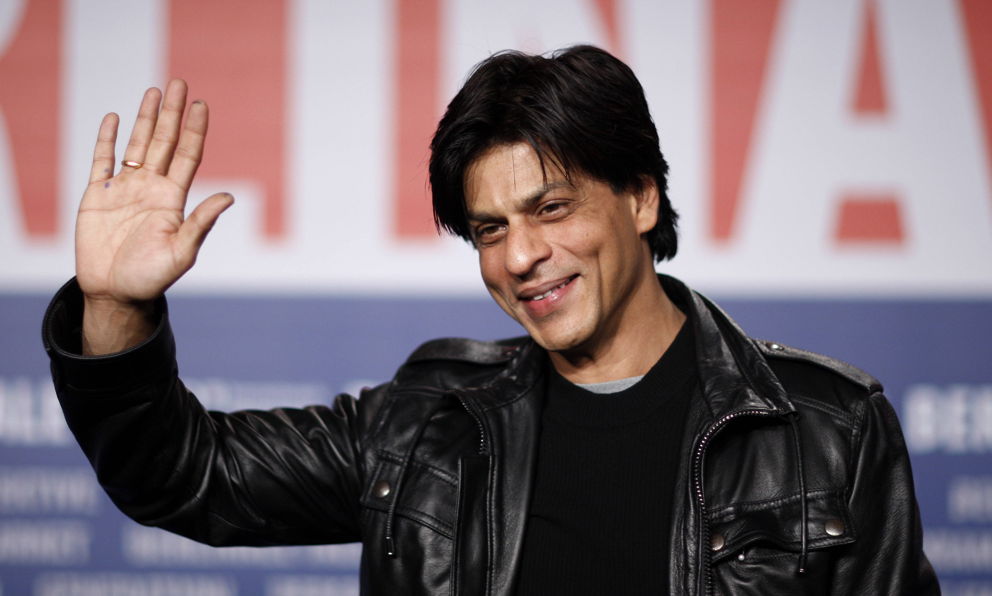Shah Rukh Khan, black leather jacket, red and blue backdrop, 2K Desktop Wallpaper