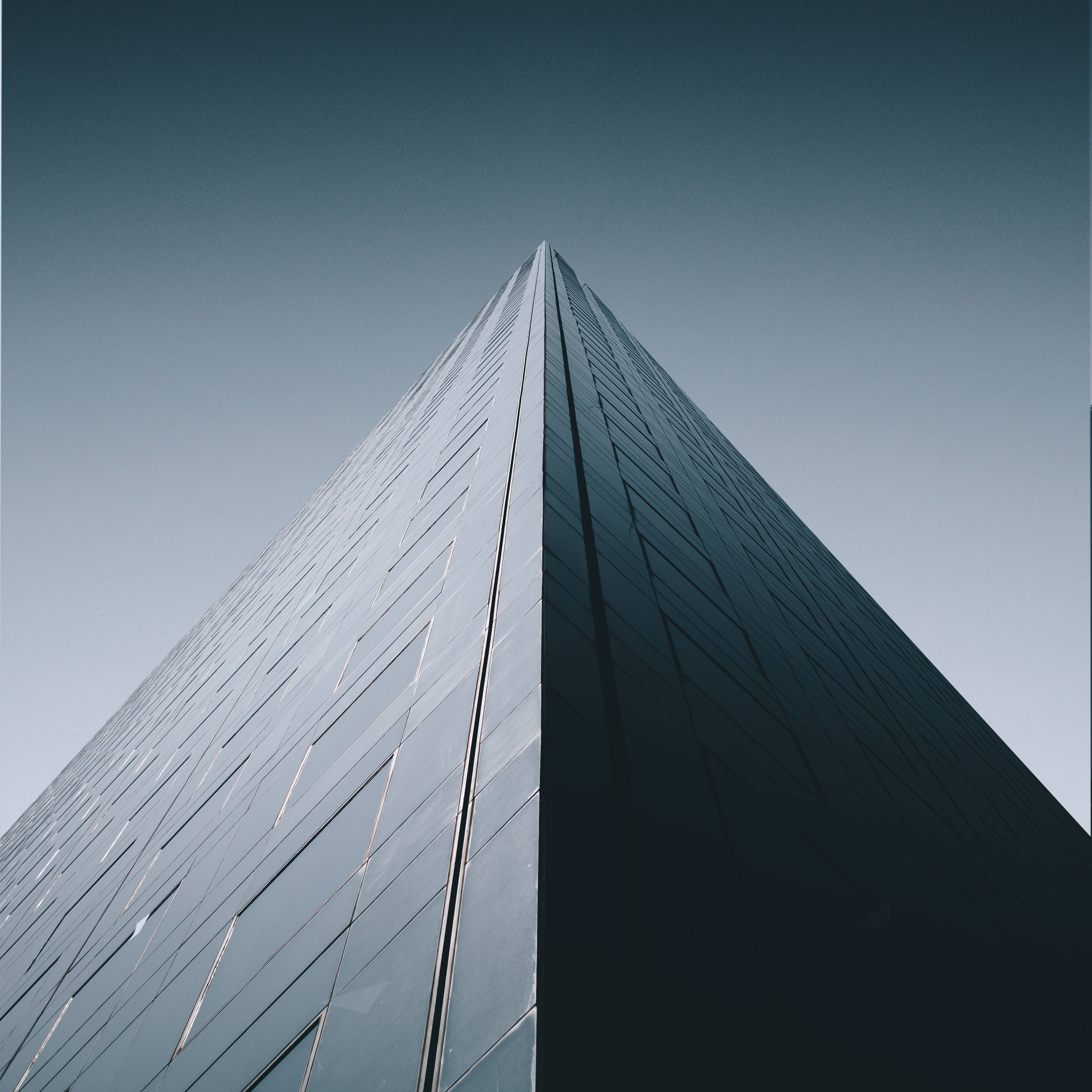 sleek glass pyramid skyscraper, gradient blue sky, low-angle shot, 2K Desktop Wallpaper