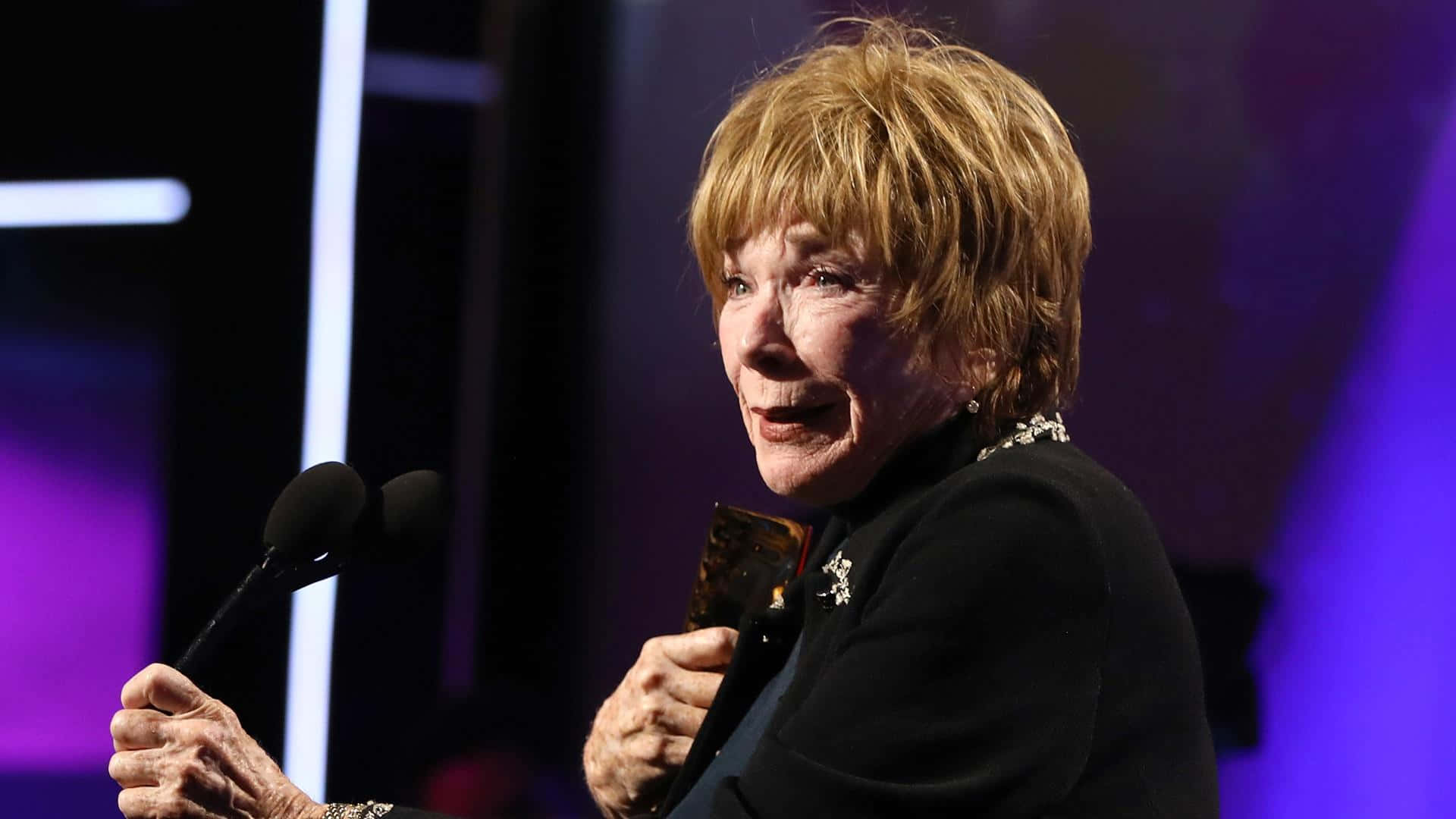 Shirley MacLaine, purple-lit stage, microphone, Full HD Desktop Wallpaper