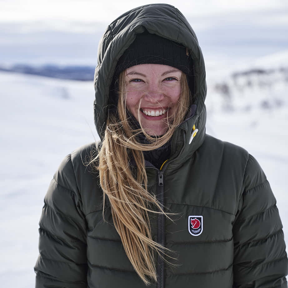 Shivering Woman, green puffer jacket, snowy mountain backdrop, SD Desktop Wallpaper