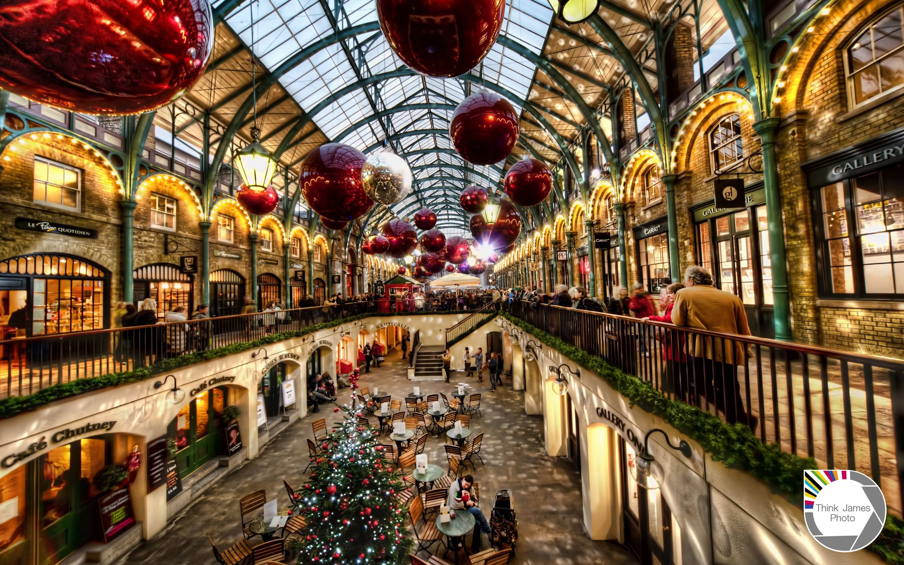 Victorian-style shopping arcade, giant red ornaments, festive Christmas tree, 2K Desktop Wallpaper