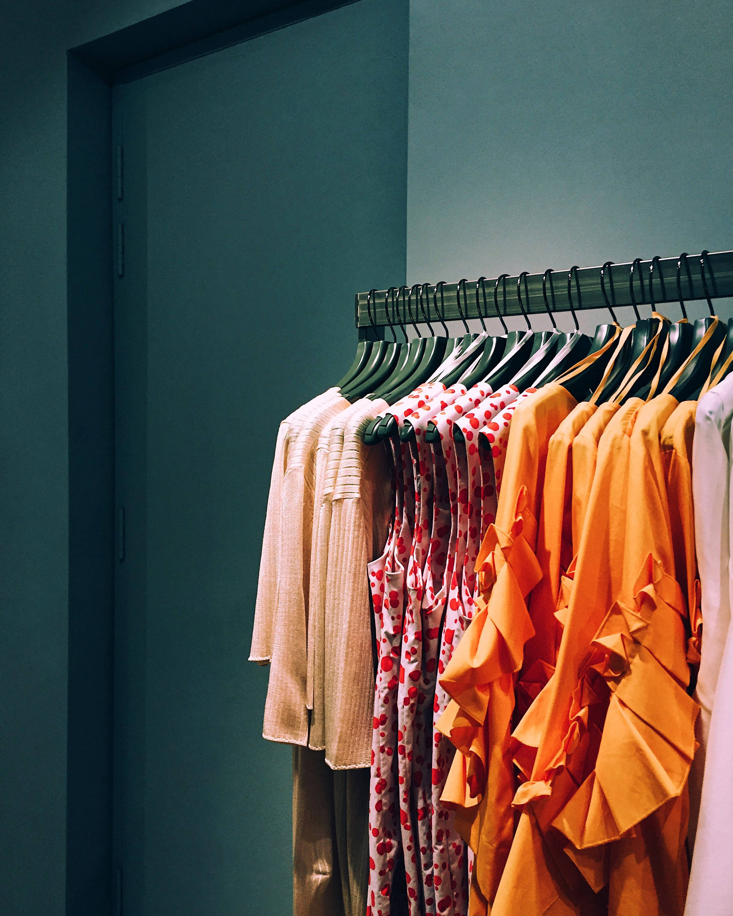 colorful garments, teal wall, dark doorway, 2K Phone Wallpaper