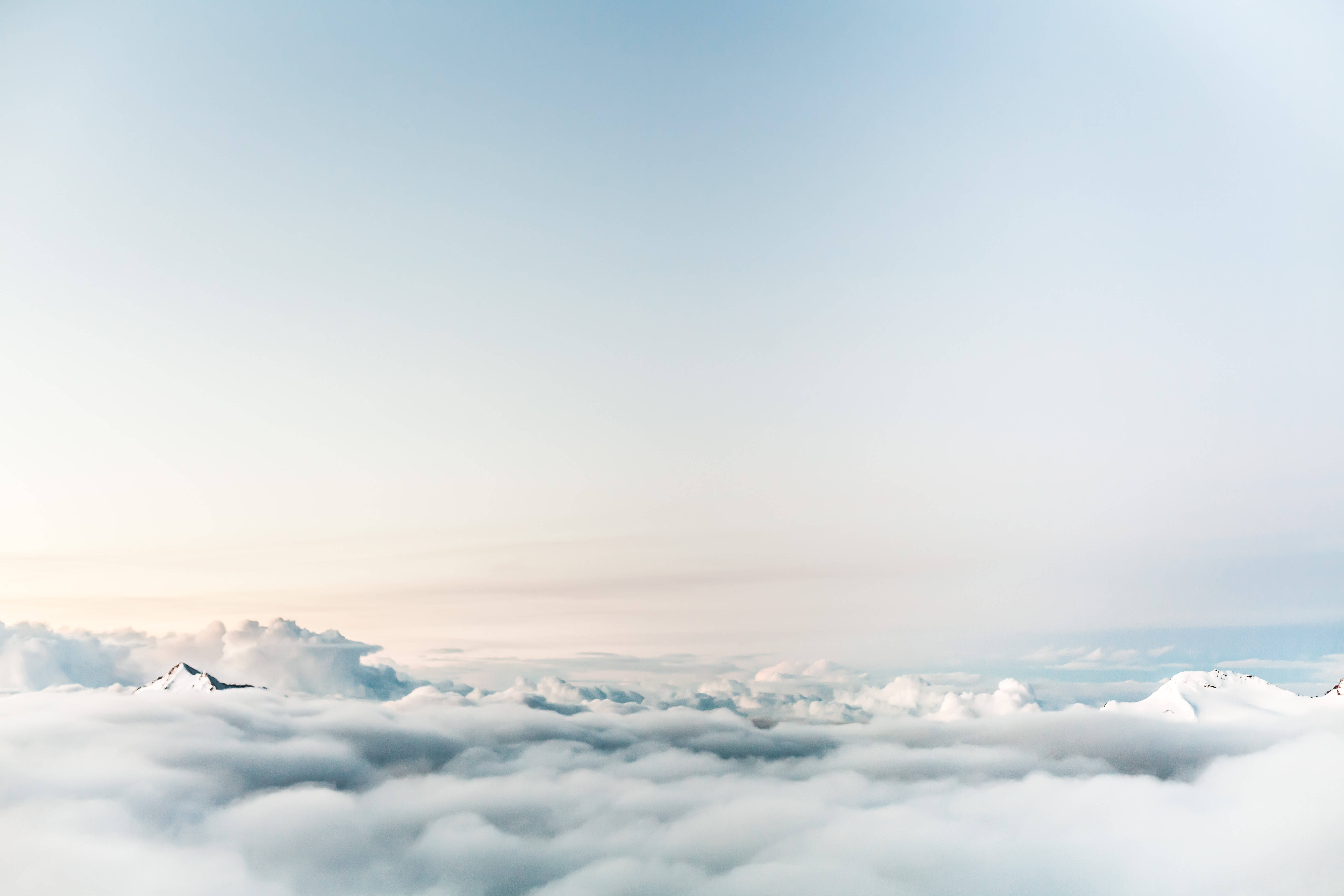 snowcapped mountain peaks, vast sea of soft white clouds, pale blue sky, 5K Desktop Wallpaper