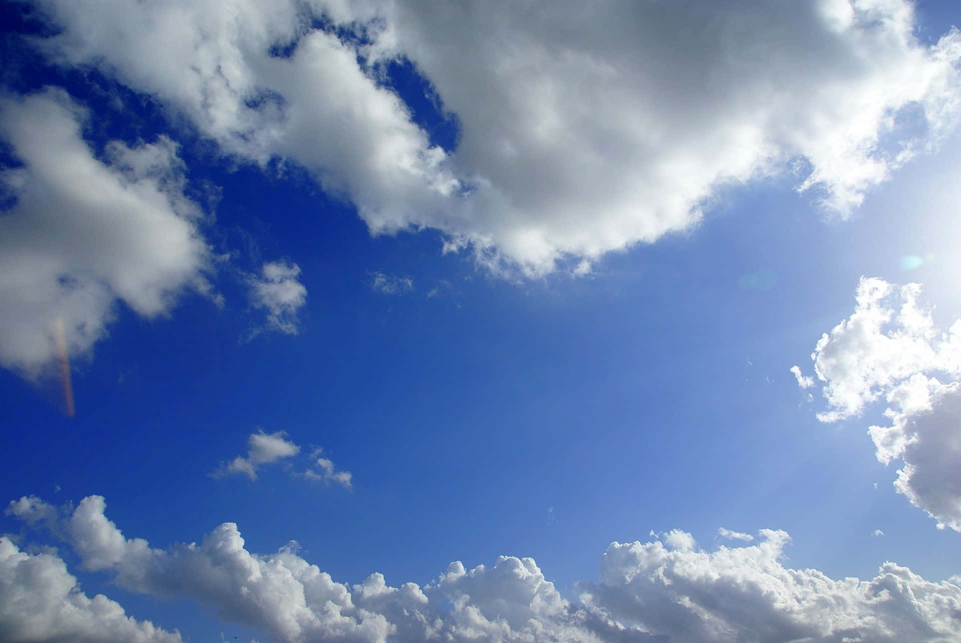 Vibrant blue sky, fluffy white clouds, bright sun flares, Full HD Desktop Wallpaper