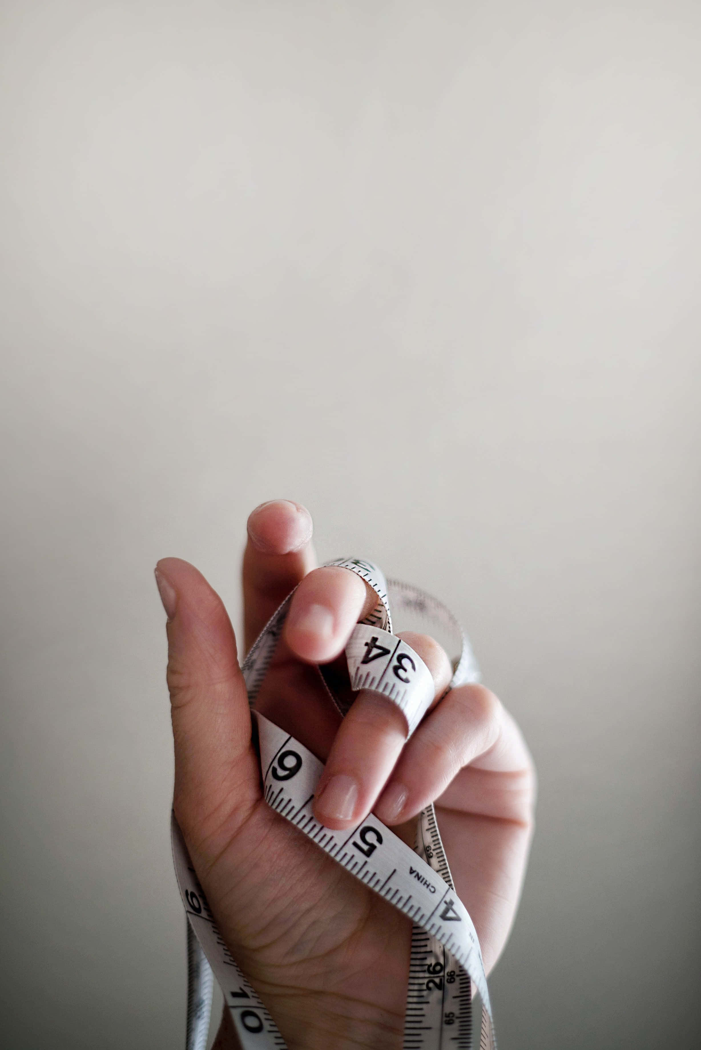 slim tape measure, white measuring tape, soft gray background, 2K Phone Wallpaper