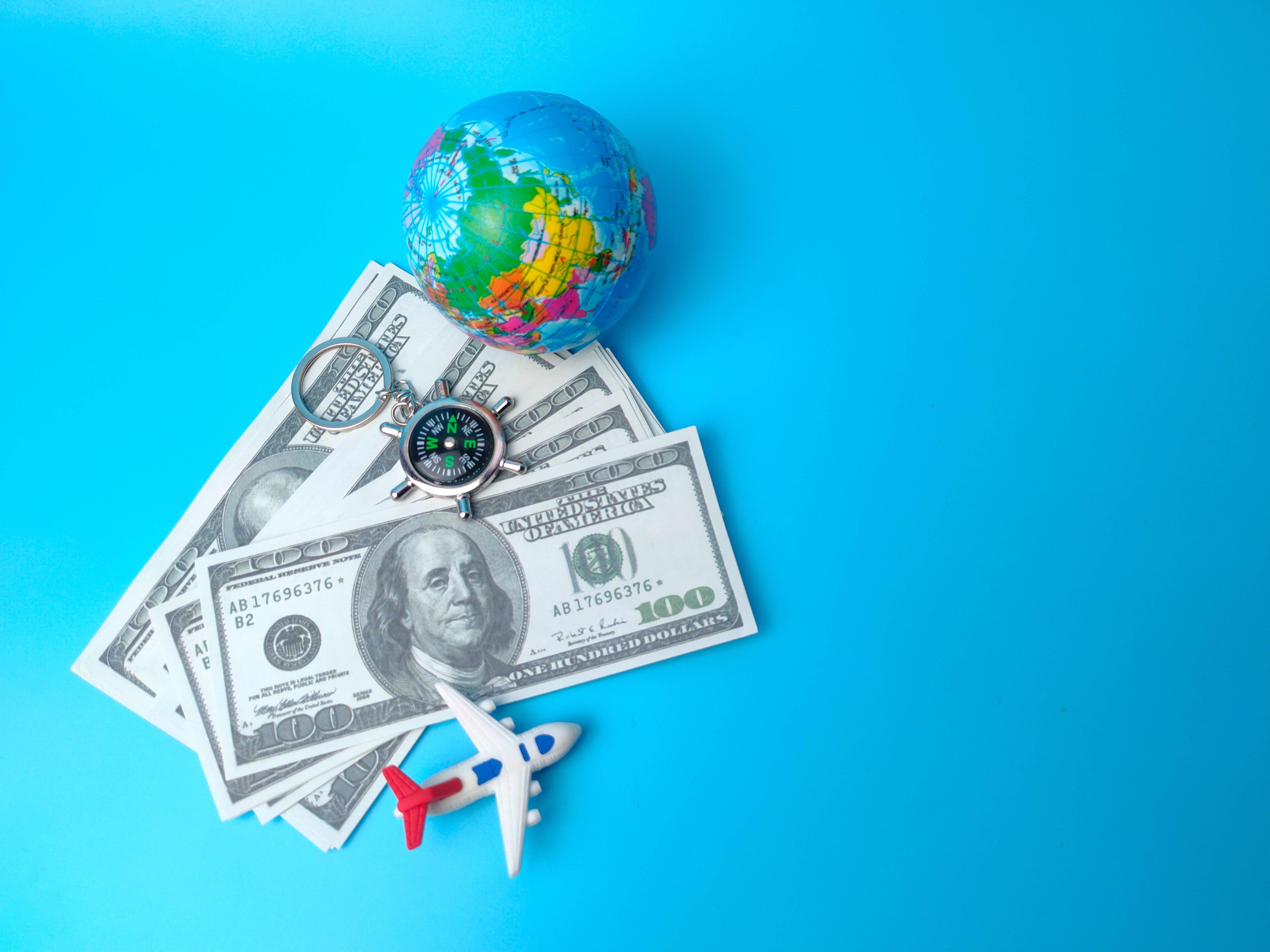 small globe compass toy airplane, hundred dollar bills, bright blue background, 4K Desktop Wallpaper