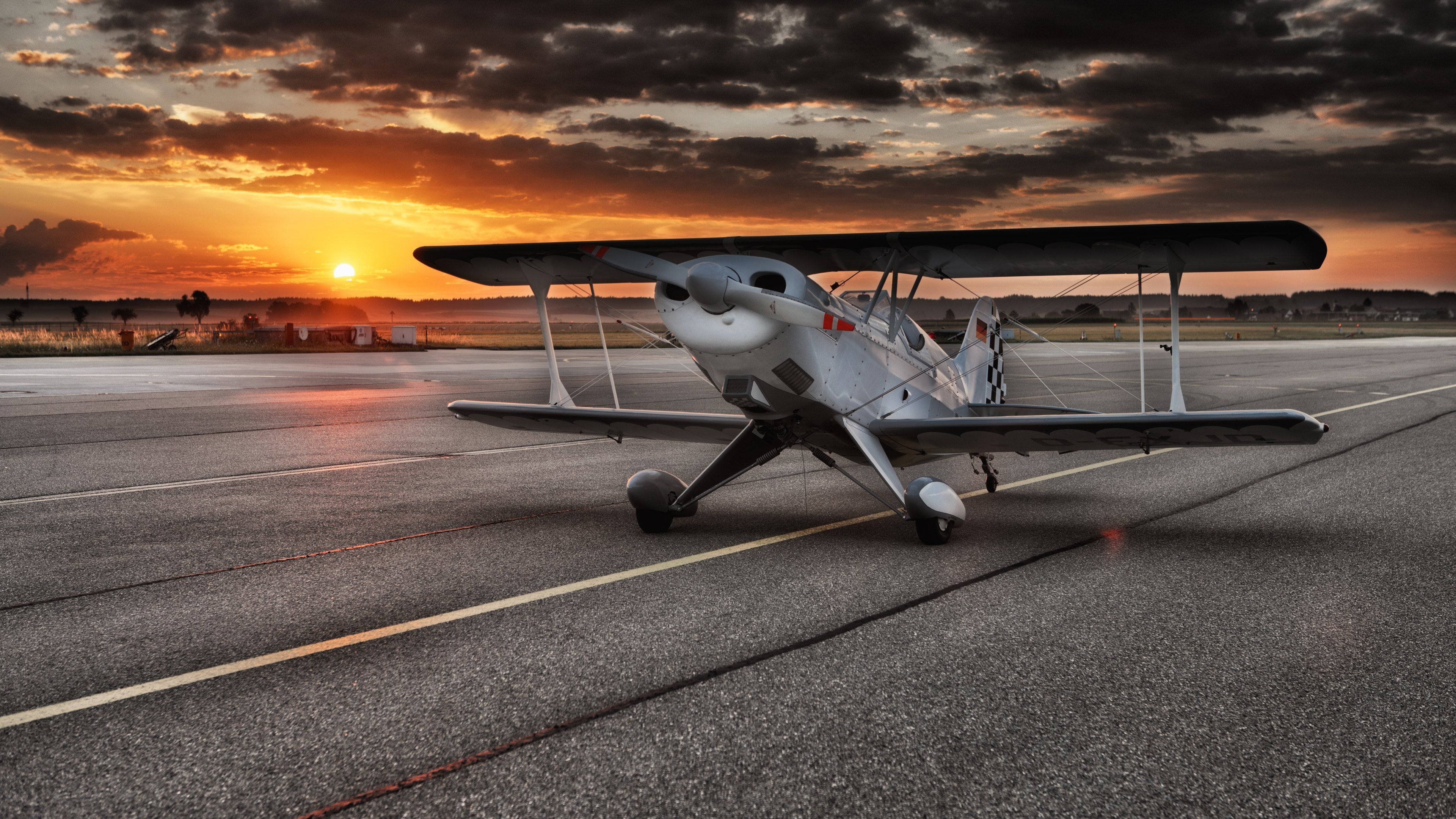 vintage biplane, airport tarmac, fiery sunset, 4K Desktop Wallpaper
