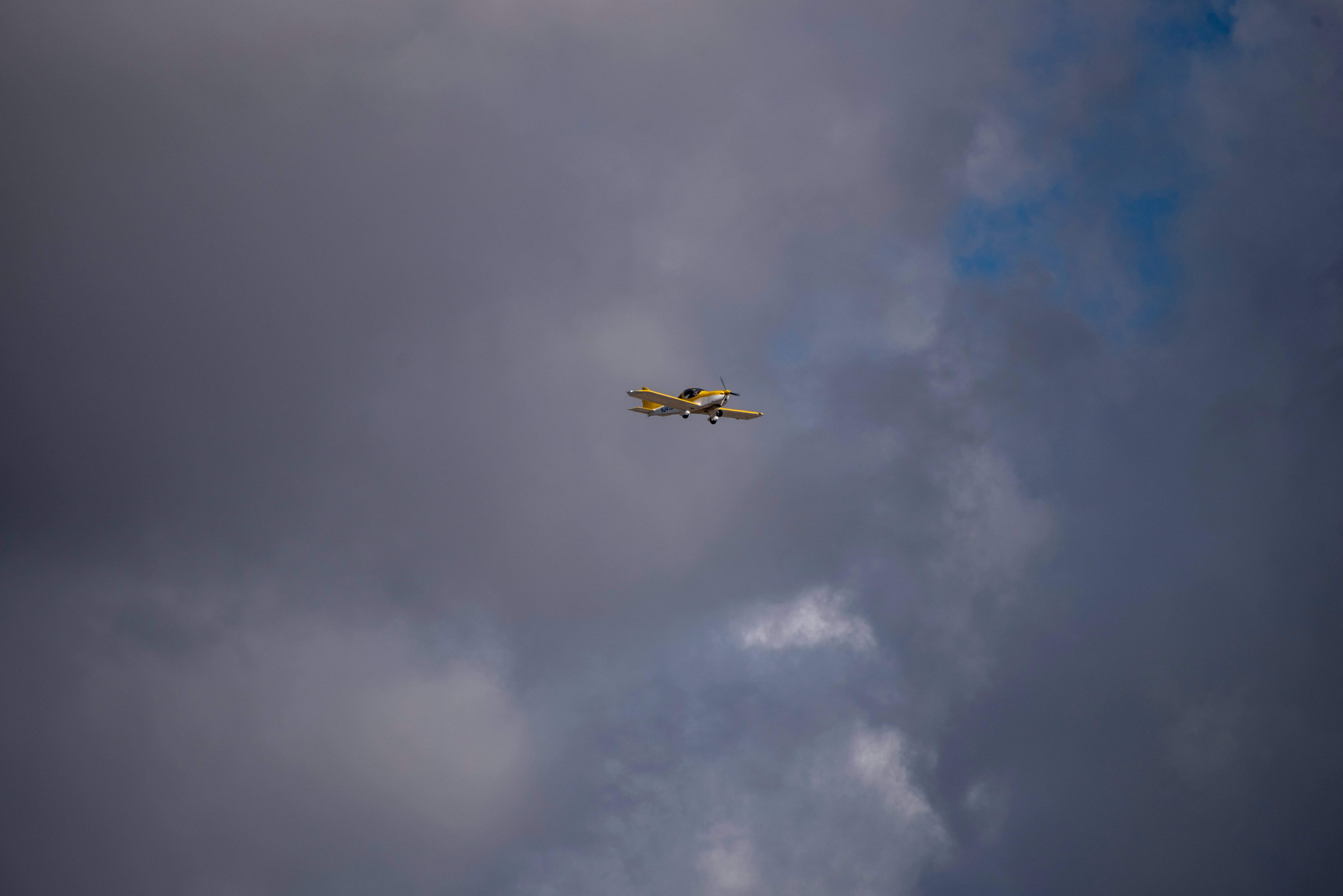 small yellow plane, sky, dark gray clouds, 5K Desktop Wallpaper