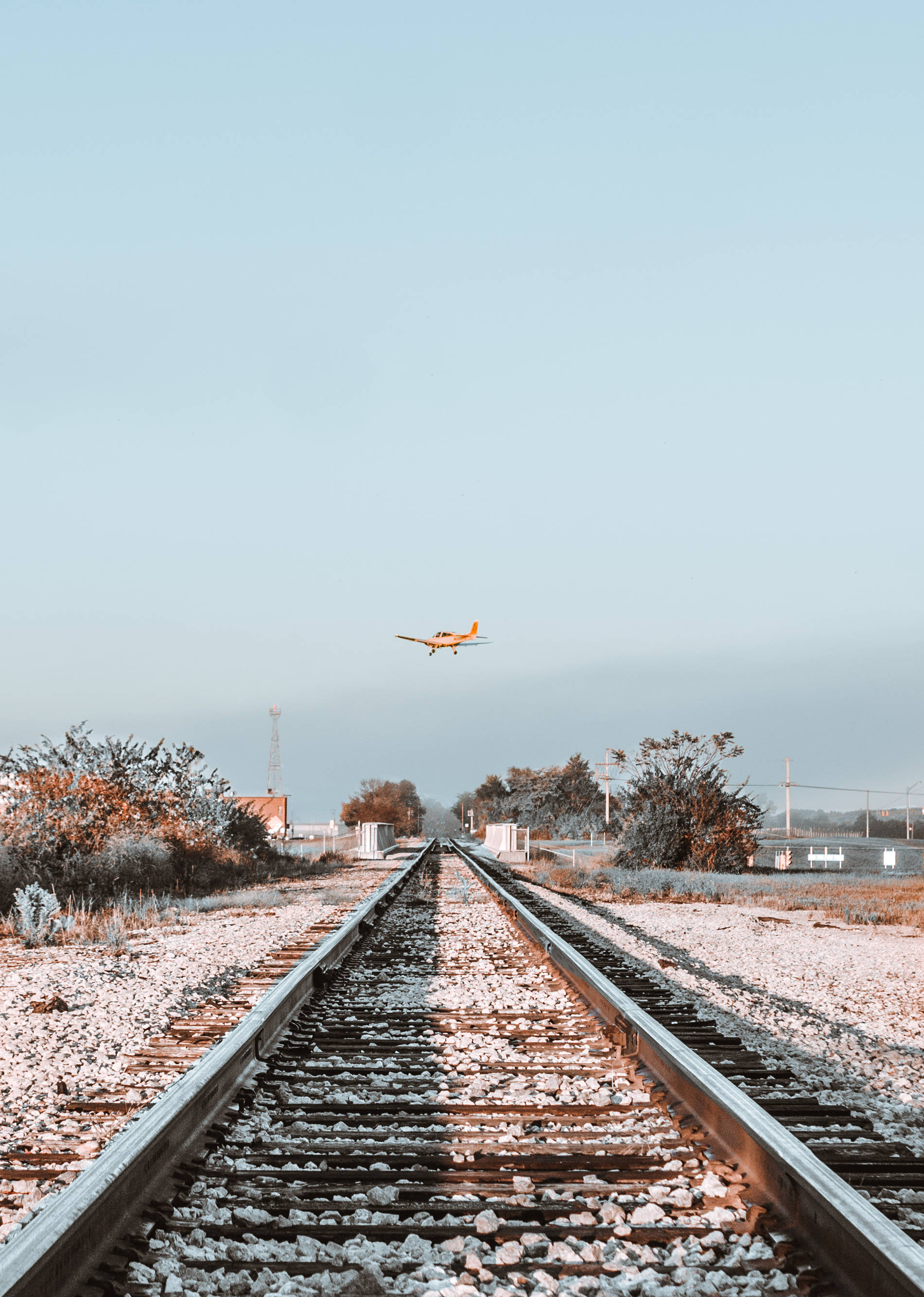 orange airplane, frost-covered railroad tracks, hazy winter landscape, 2K Phone Wallpaper