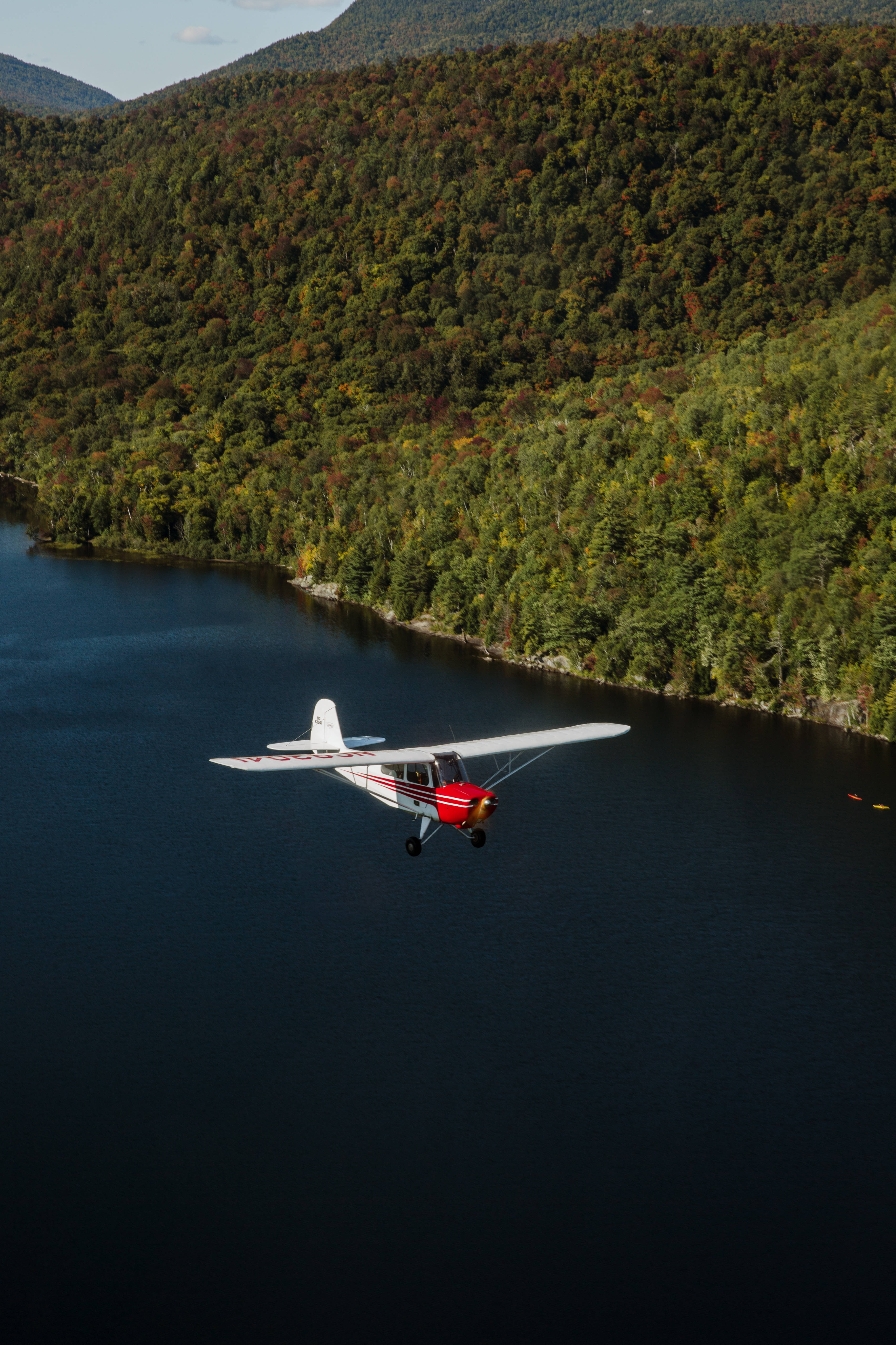 red and white single-engine plane, dark lake, dense autumn forested hills, 5K Phone Wallpaper