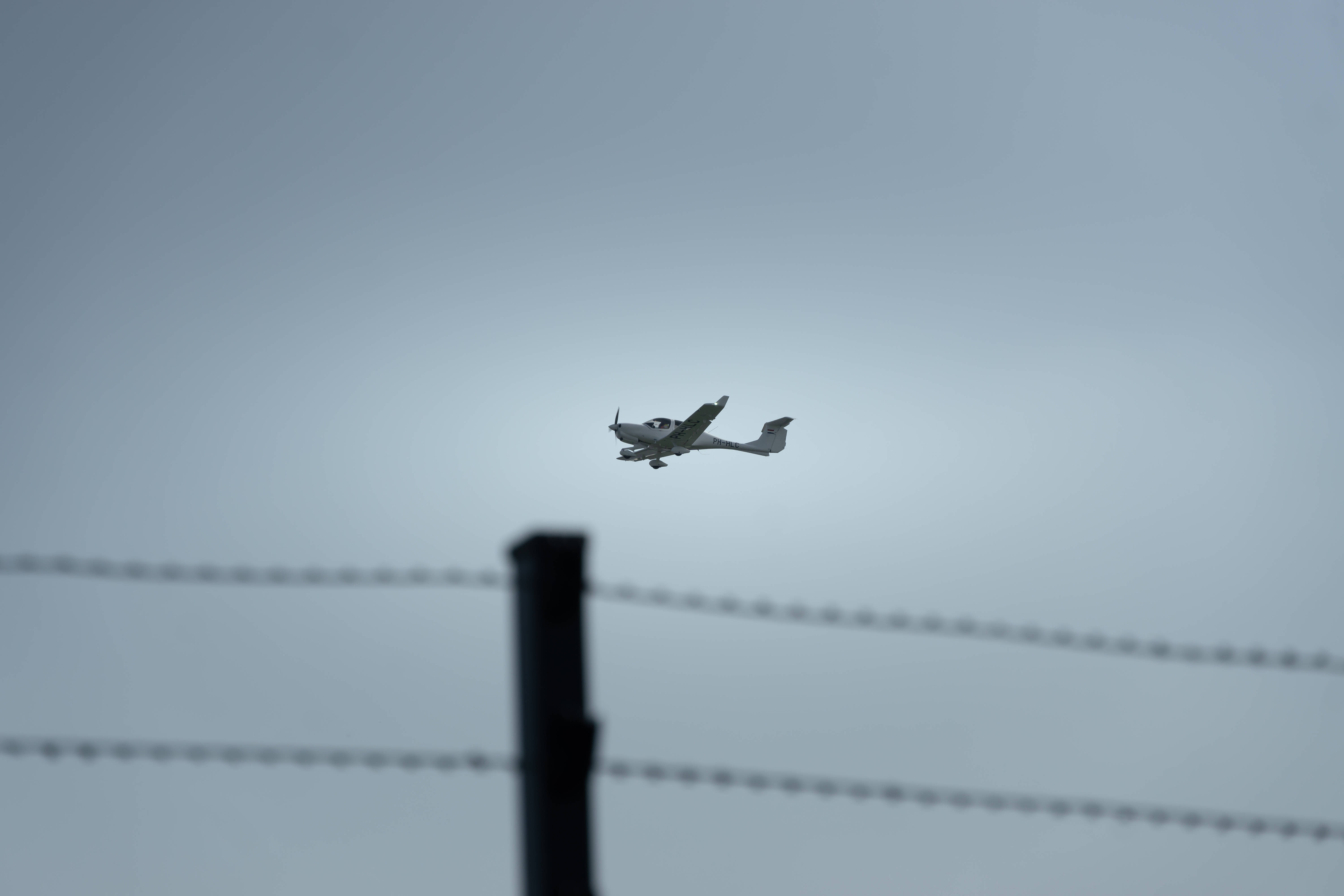 small propeller plane, pale gray sky, barbed wire, 5K Desktop Wallpaper