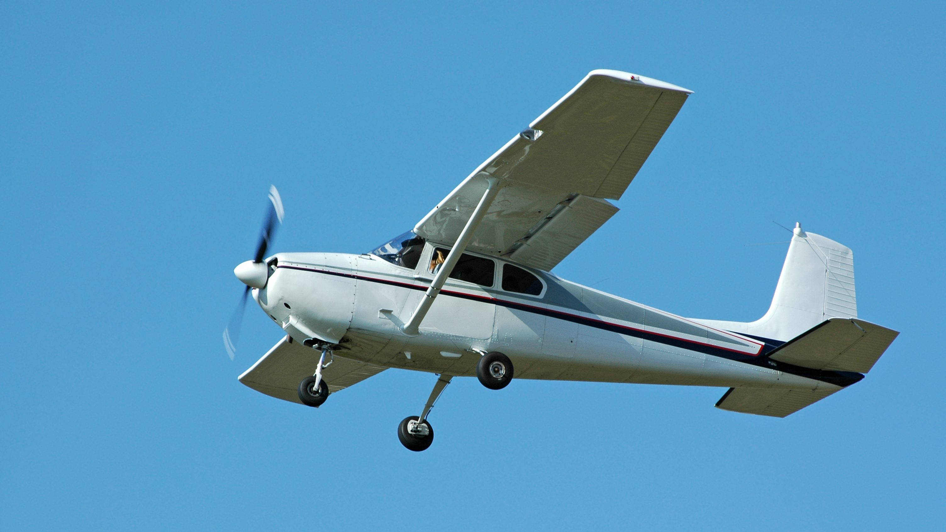 white, single-engine propeller plane, landing gear down, 2K Desktop Wallpaper