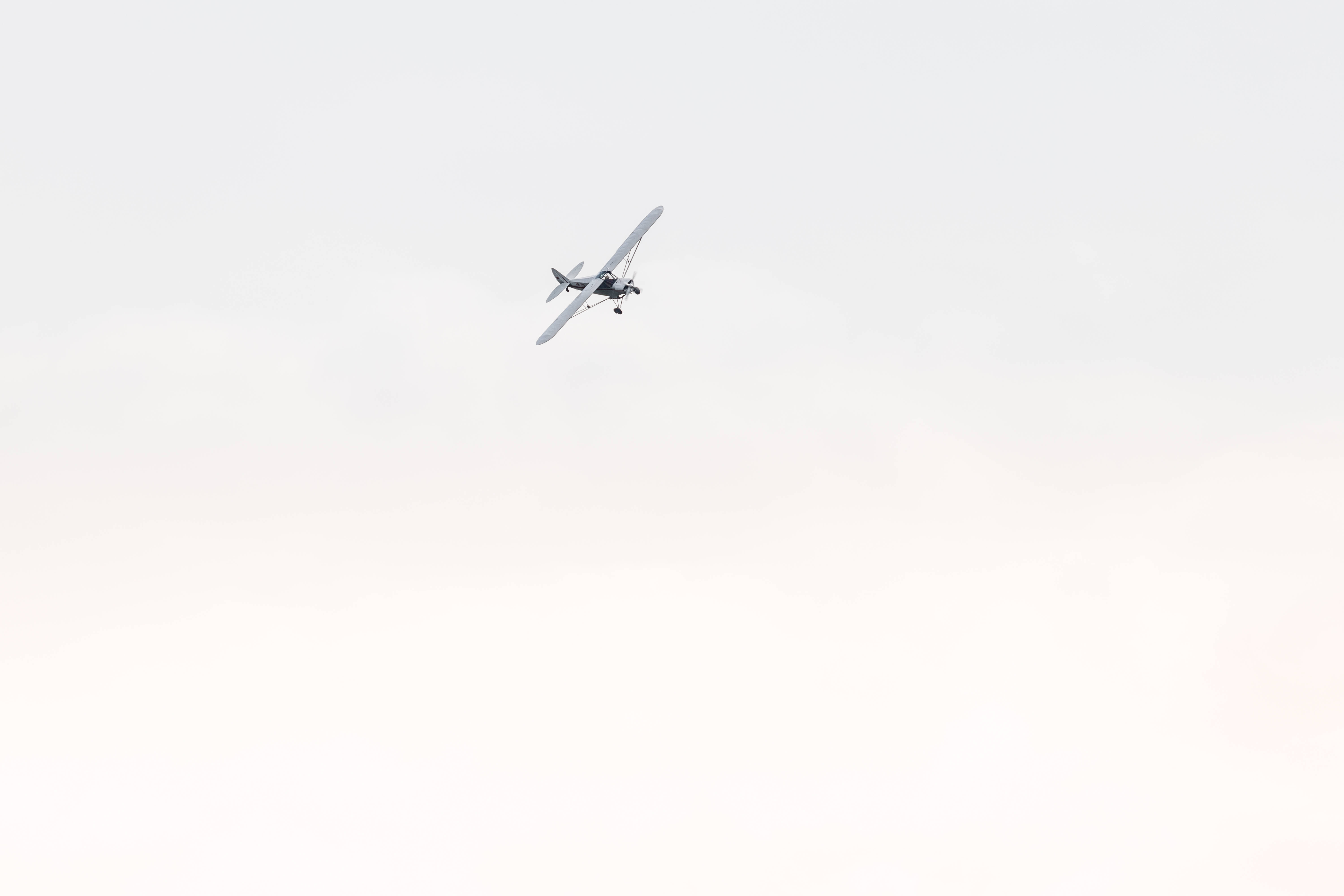 small single-engine airplane, vast pale sky, soft cloud cover, 5K Desktop Wallpaper