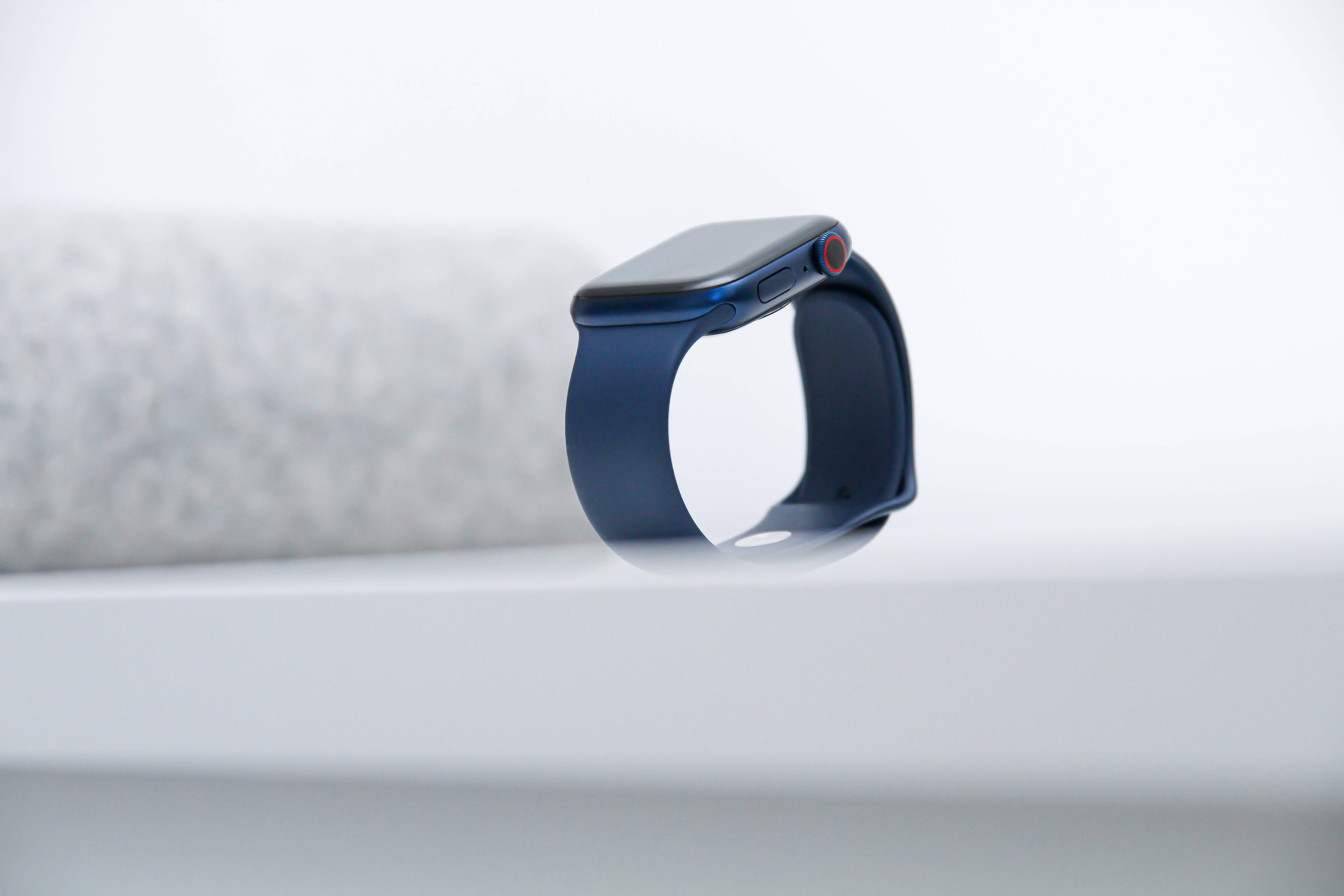blue smartwatch, minimalist white surface, soft gray textured background, 5K Desktop Wallpaper