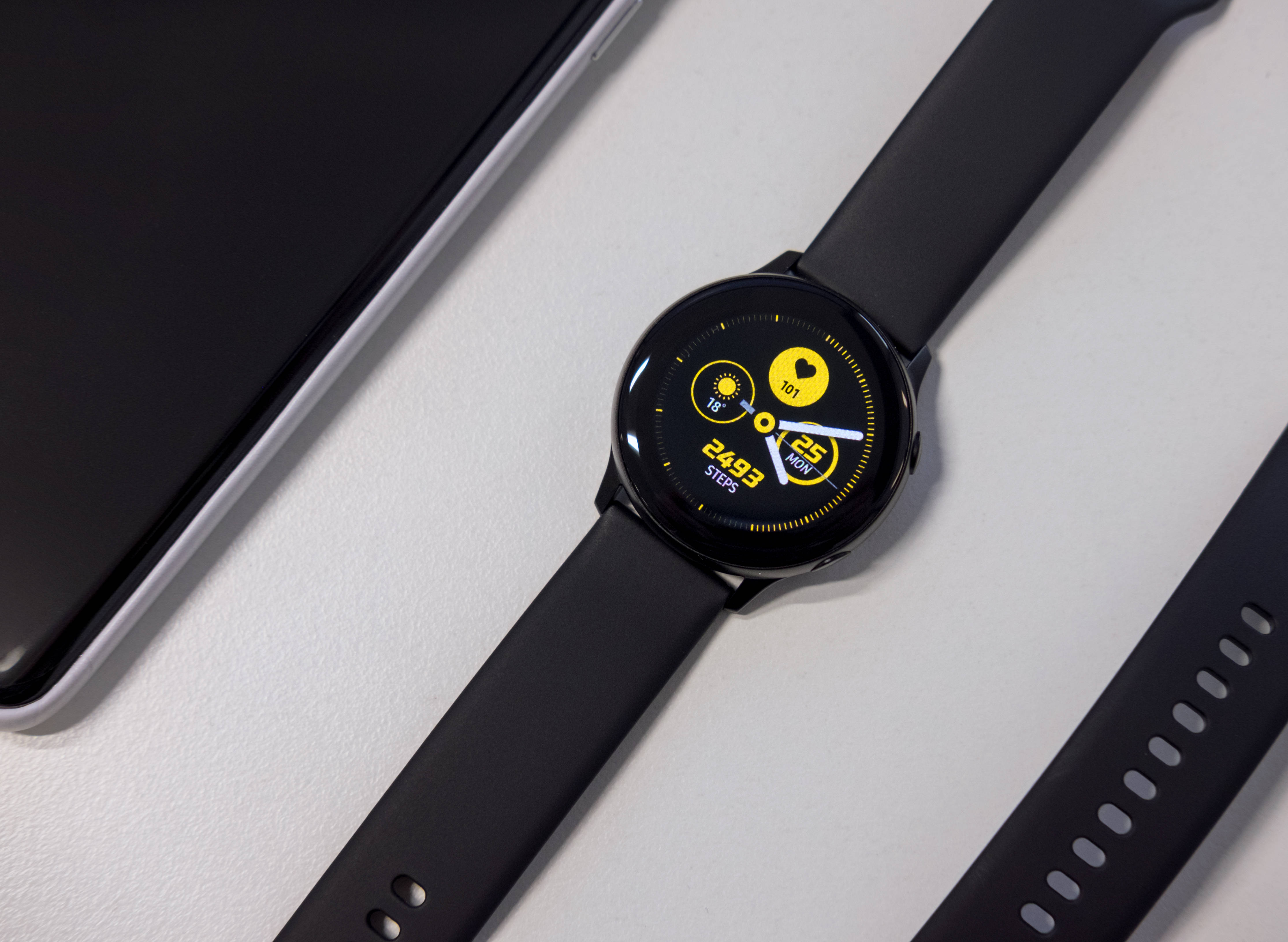 sleek black smartwatch, vibrant yellow fitness display, minimalist white surface, 4K Desktop Wallpaper