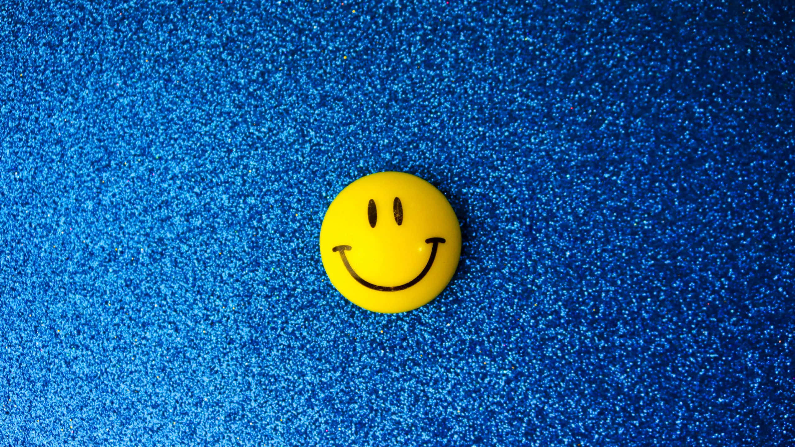 yellow smile emoji, blue glitter background, smiley face button, 2K Desktop Wallpaper