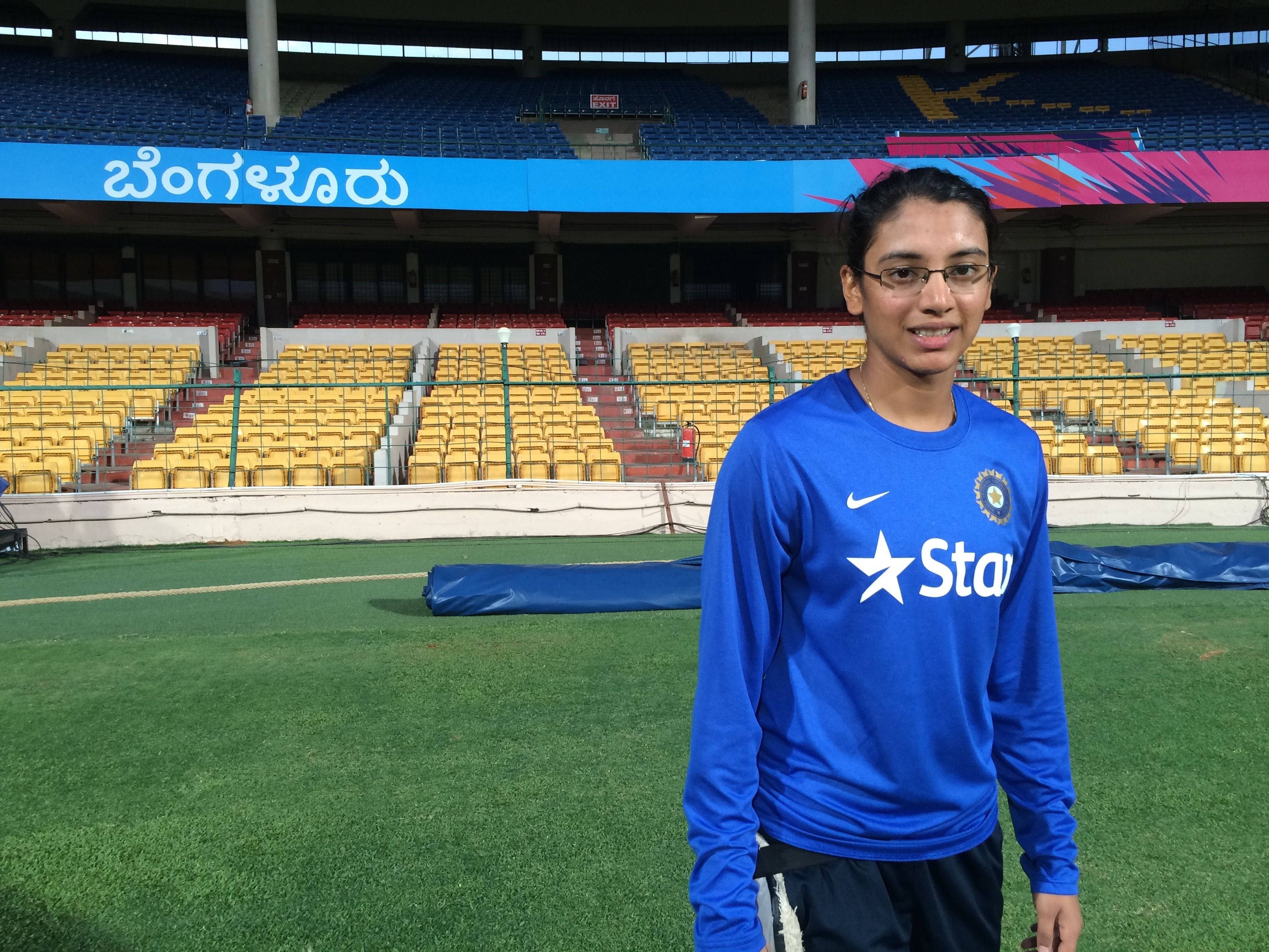 Smriti Mandhana, blue India cricket training jersey, empty green turf field, 2K Desktop Wallpaper