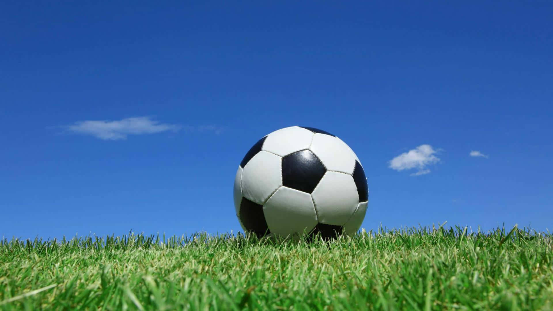 classic black and white soccer ball, vibrant green grass, clear blue sky, Full HD Desktop Wallpaper