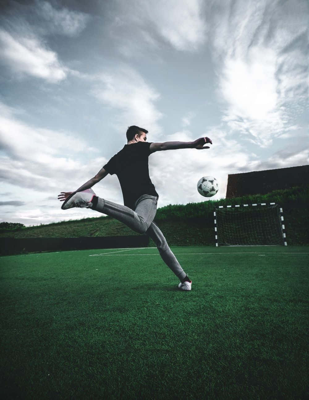 classic black and white soccer ball, vibrant green field, dramatic cloudy sky, HD Phone Wallpaper