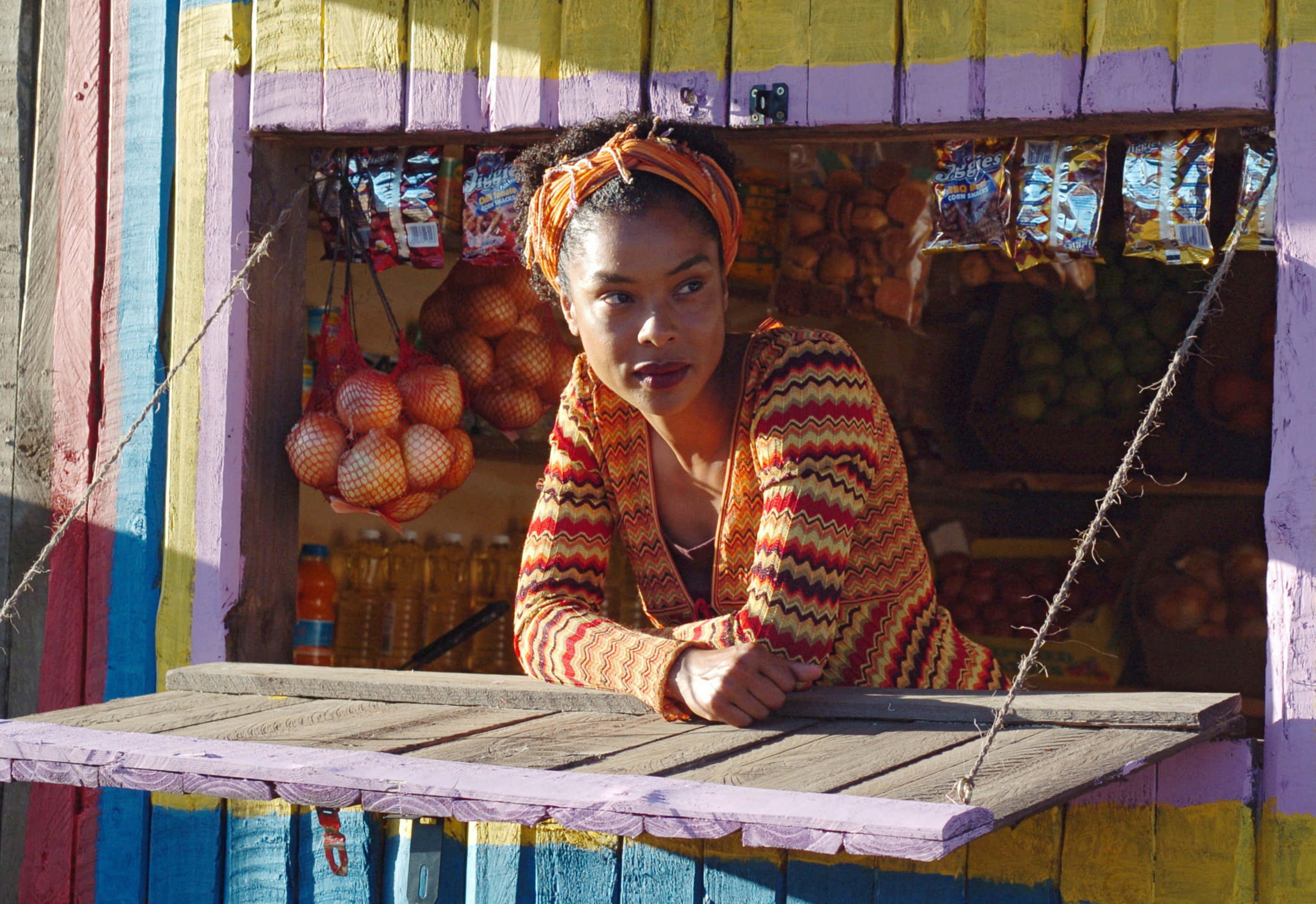 Sophie Okonedo, colorful zigzag sweater, wooden stall, 2K Desktop Wallpaper