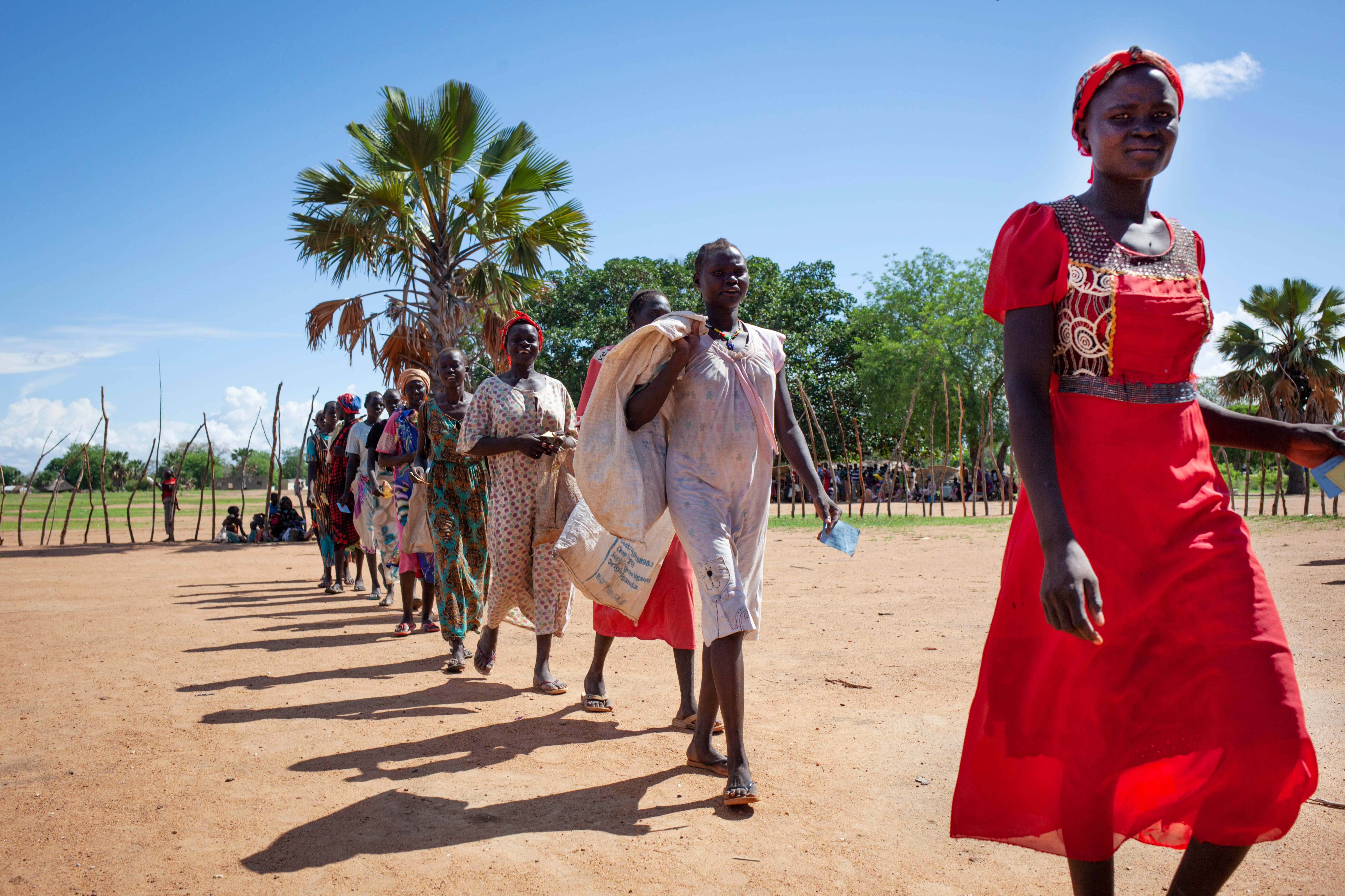 South Sudan, vibrant traditional attire, sunlit dirt field, 5K Desktop Wallpaper