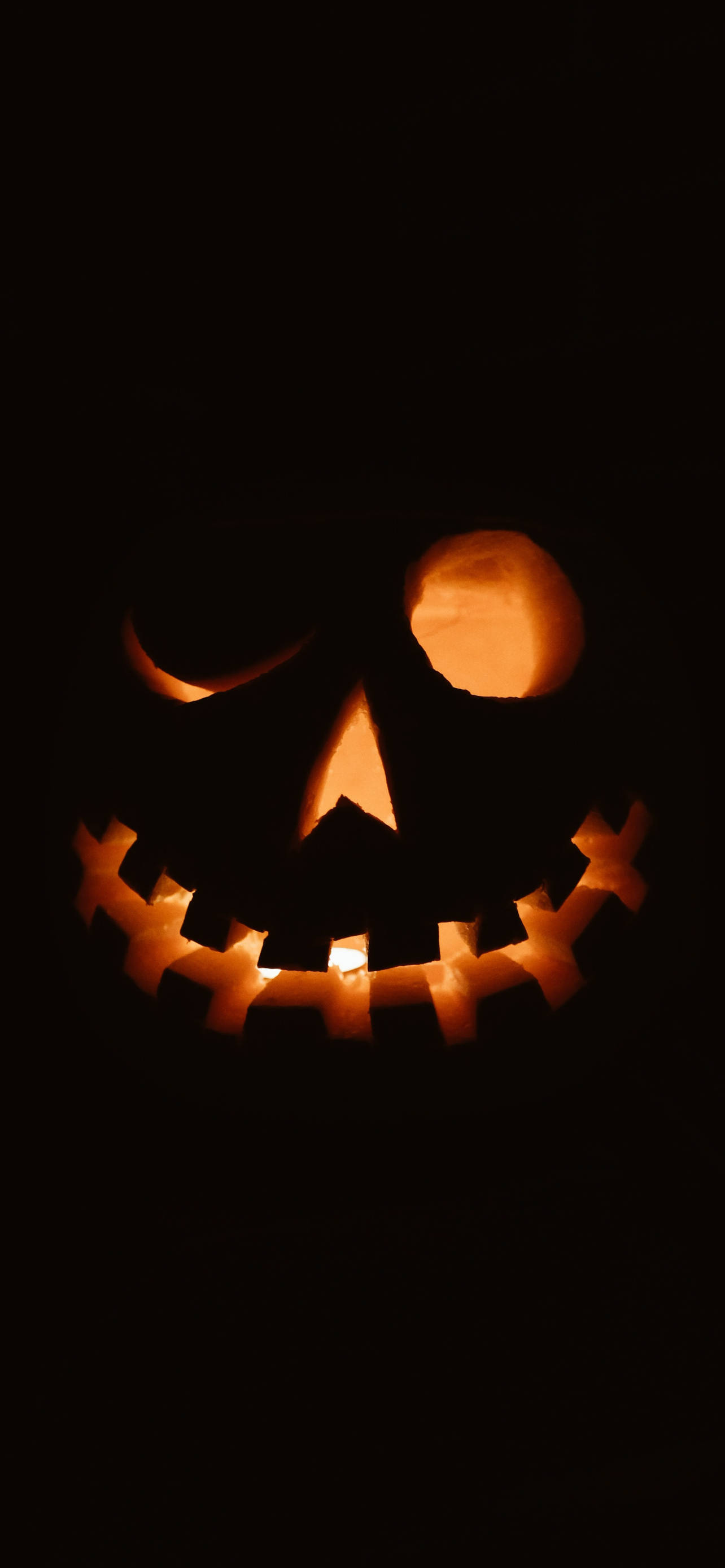 jack-o'-lantern, mischievous grin, dark background, 2K Phone Wallpaper
