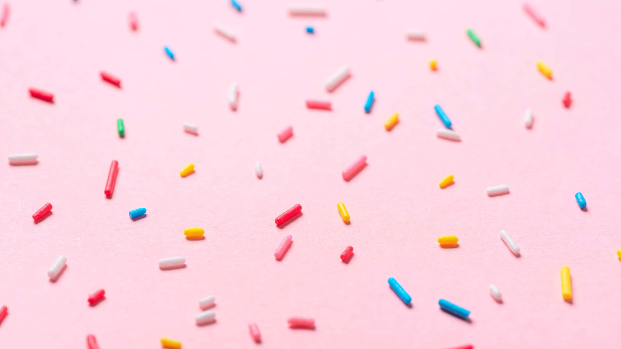 colorful sprinkles, pink background, flat lay composition, 2K Desktop Wallpaper