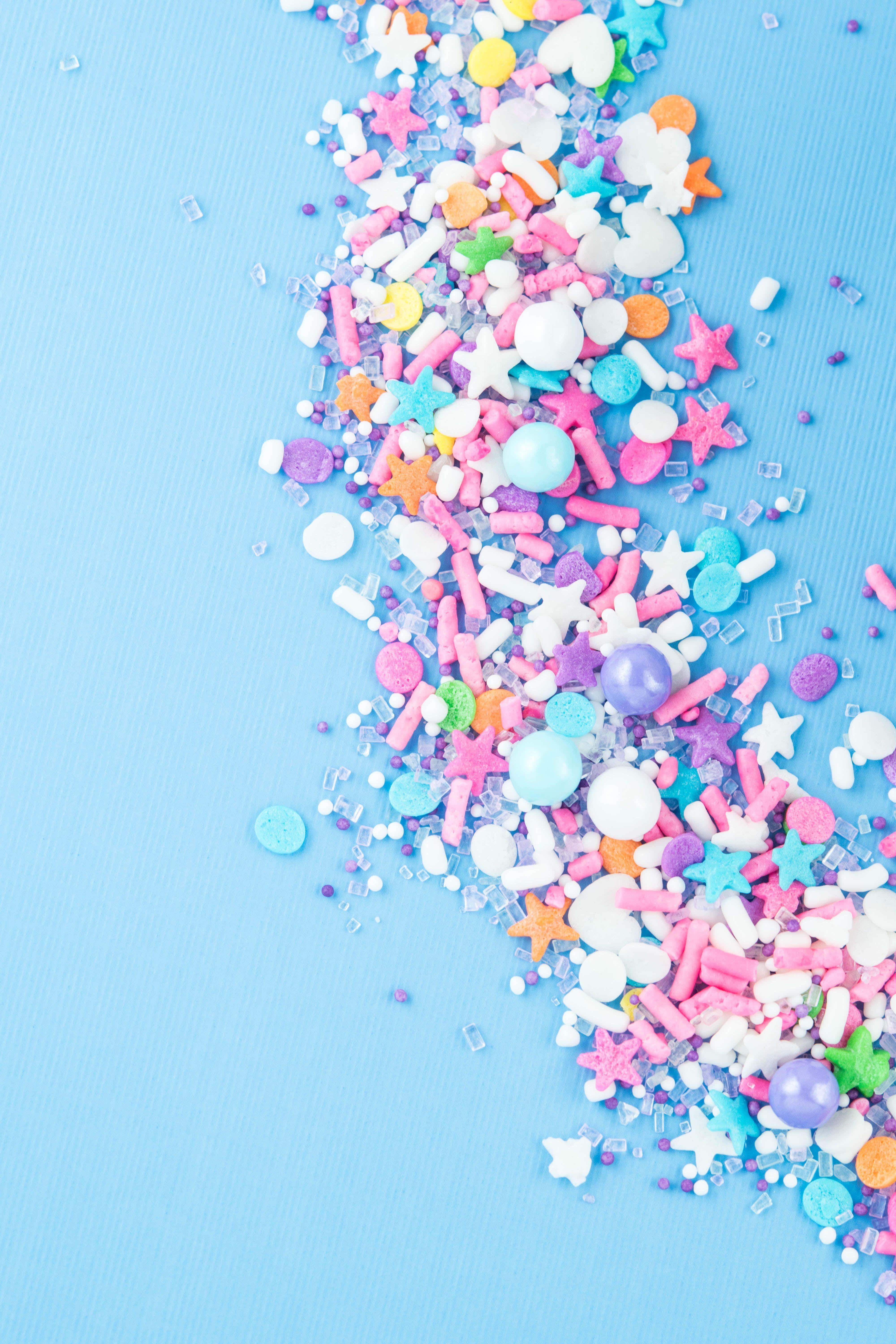 colorful sprinkles, pastel-colored star and ball sprinkles, smooth light blue surface, 5K Phone Wallpaper
