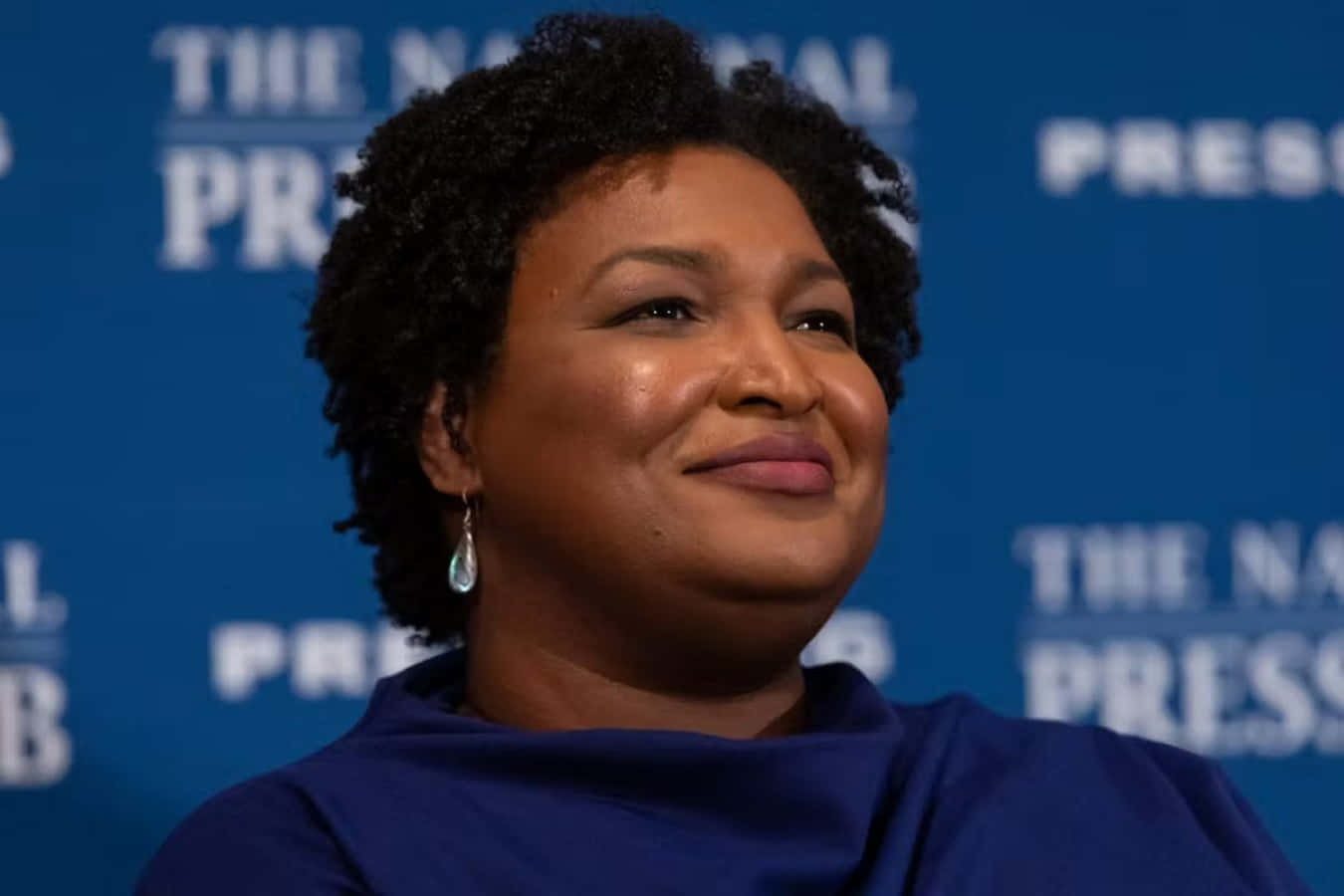 Stacey Abrams, blue press backdrop, white text, HD Desktop Wallpaper