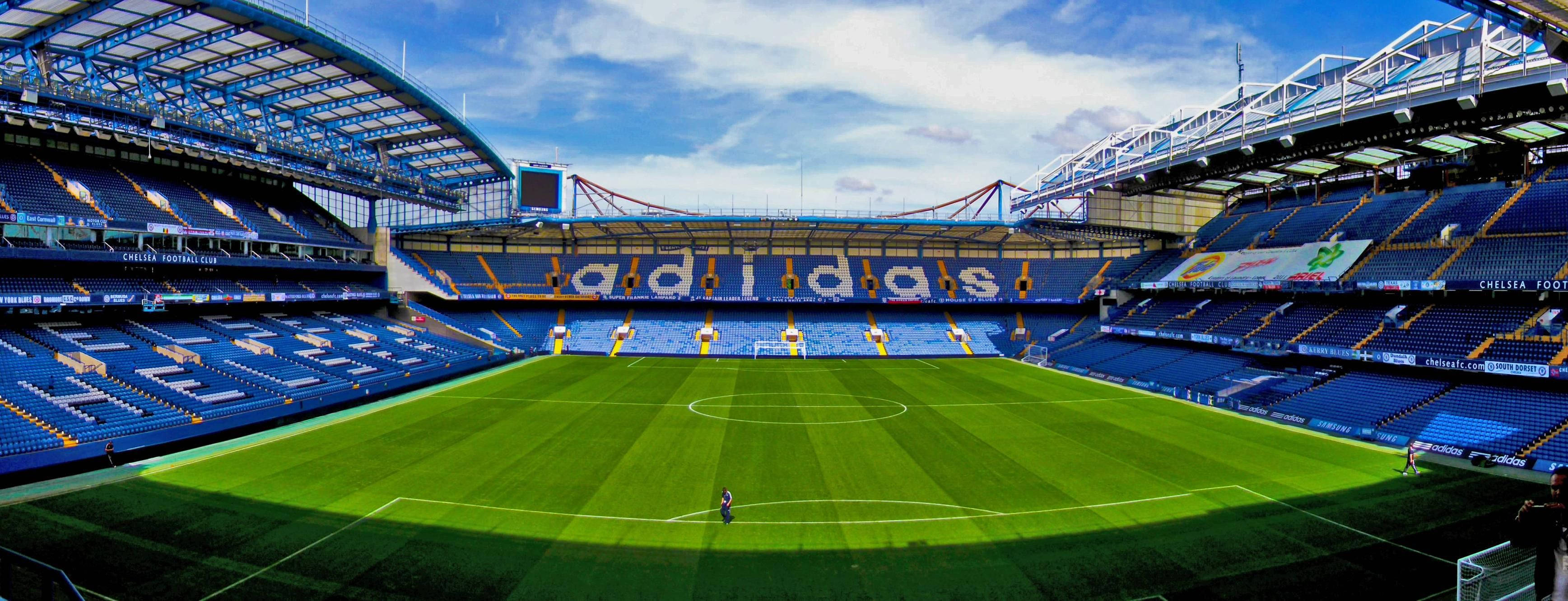 Stamford Bridge, vast empty football stadium, vibrant green grass, 2K Desktop Wallpaper