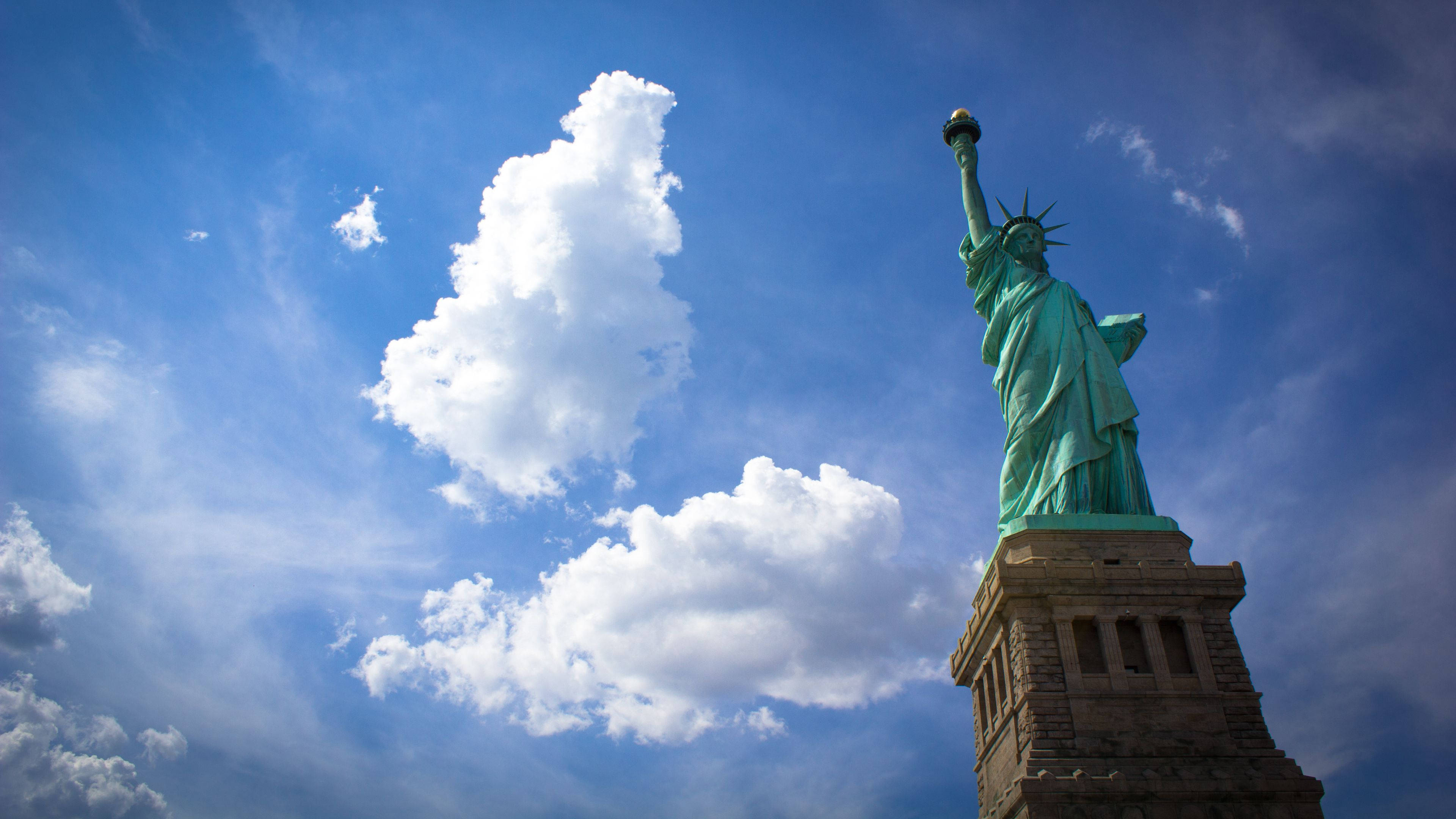 Statue Of Liberty, vibrant blue sky, fluffy white clouds, 4K Desktop Wallpaper