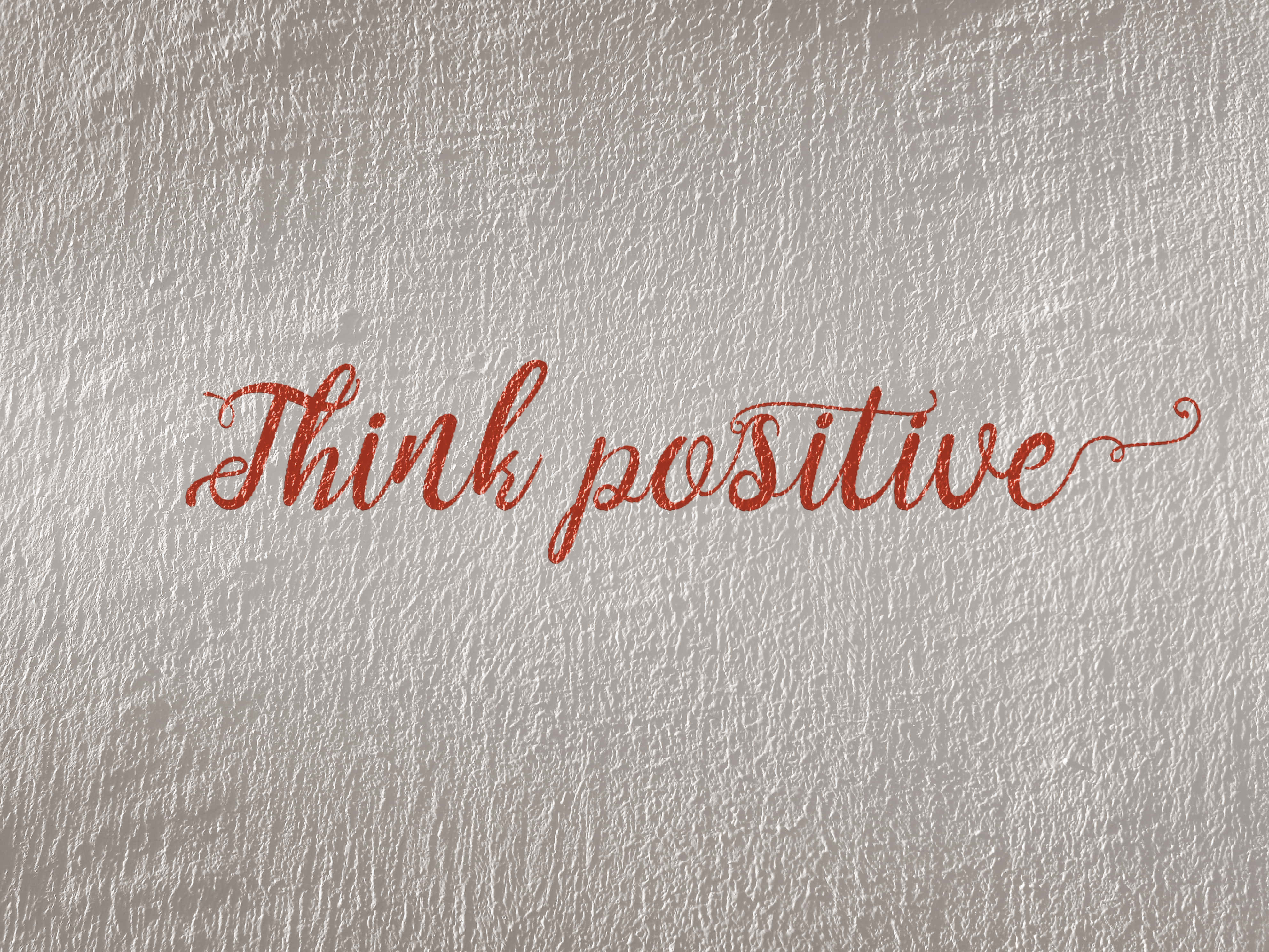 Think positive, elegant red cursive script, textured silver-gray wall, 4K Desktop Wallpaper