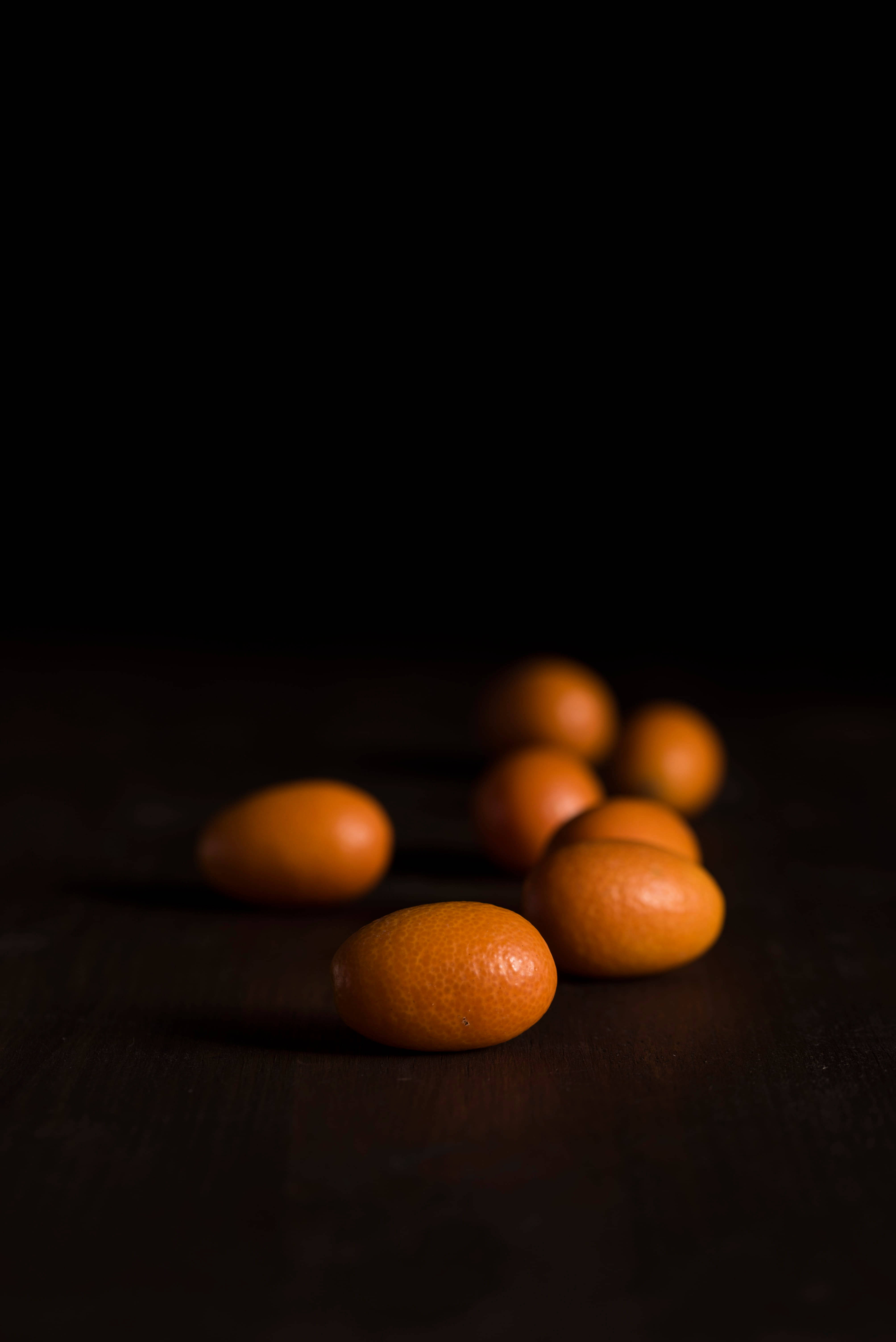 dark kumquat fruits, eye level shot, glowing orange kumquats, 5K Phone Wallpaper