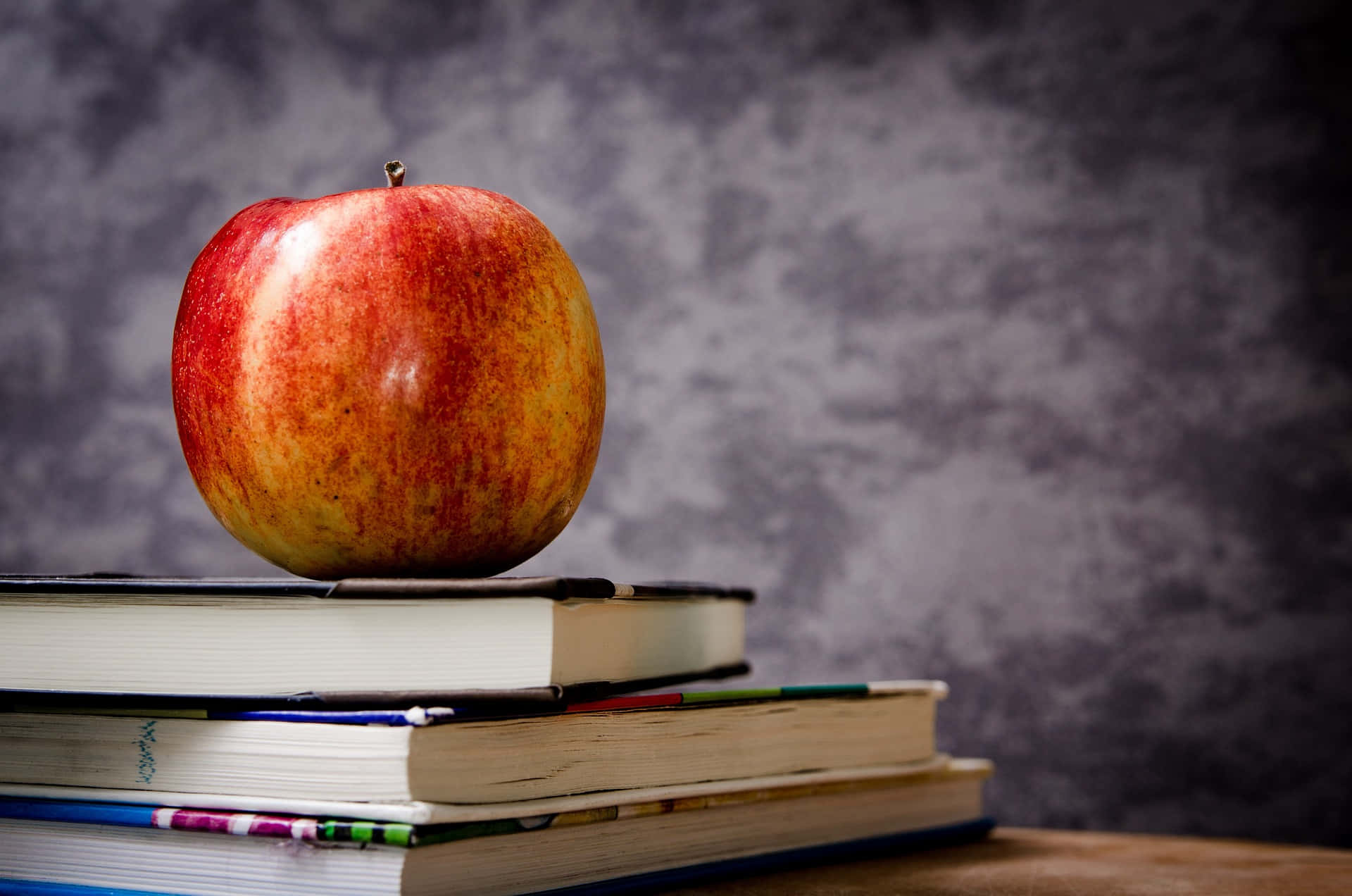 glossy red apple, stack of colorful books, textured gray backdrop, Full HD Desktop Wallpaper