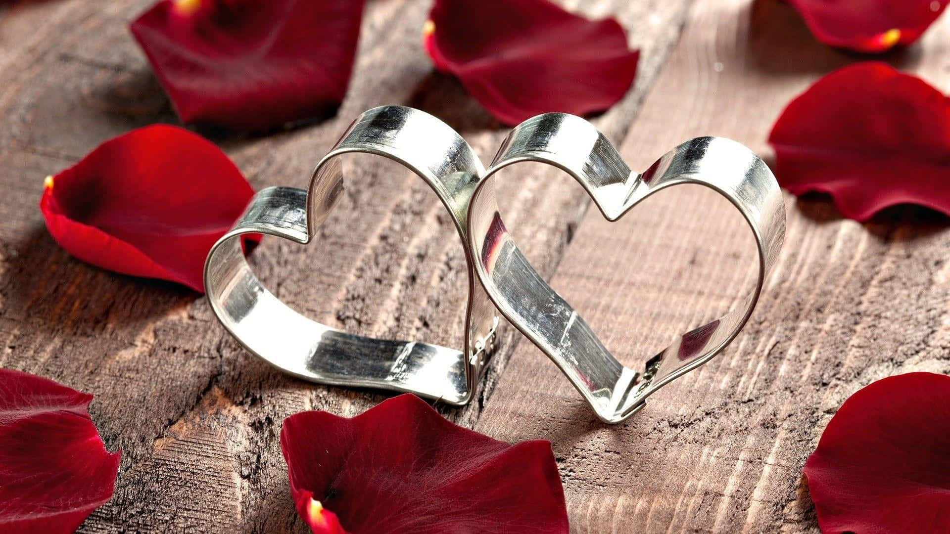 rustic wooden surface, shiny silver heart-shaped cookie cutters, deep red rose petals, Full HD Desktop Wallpaper