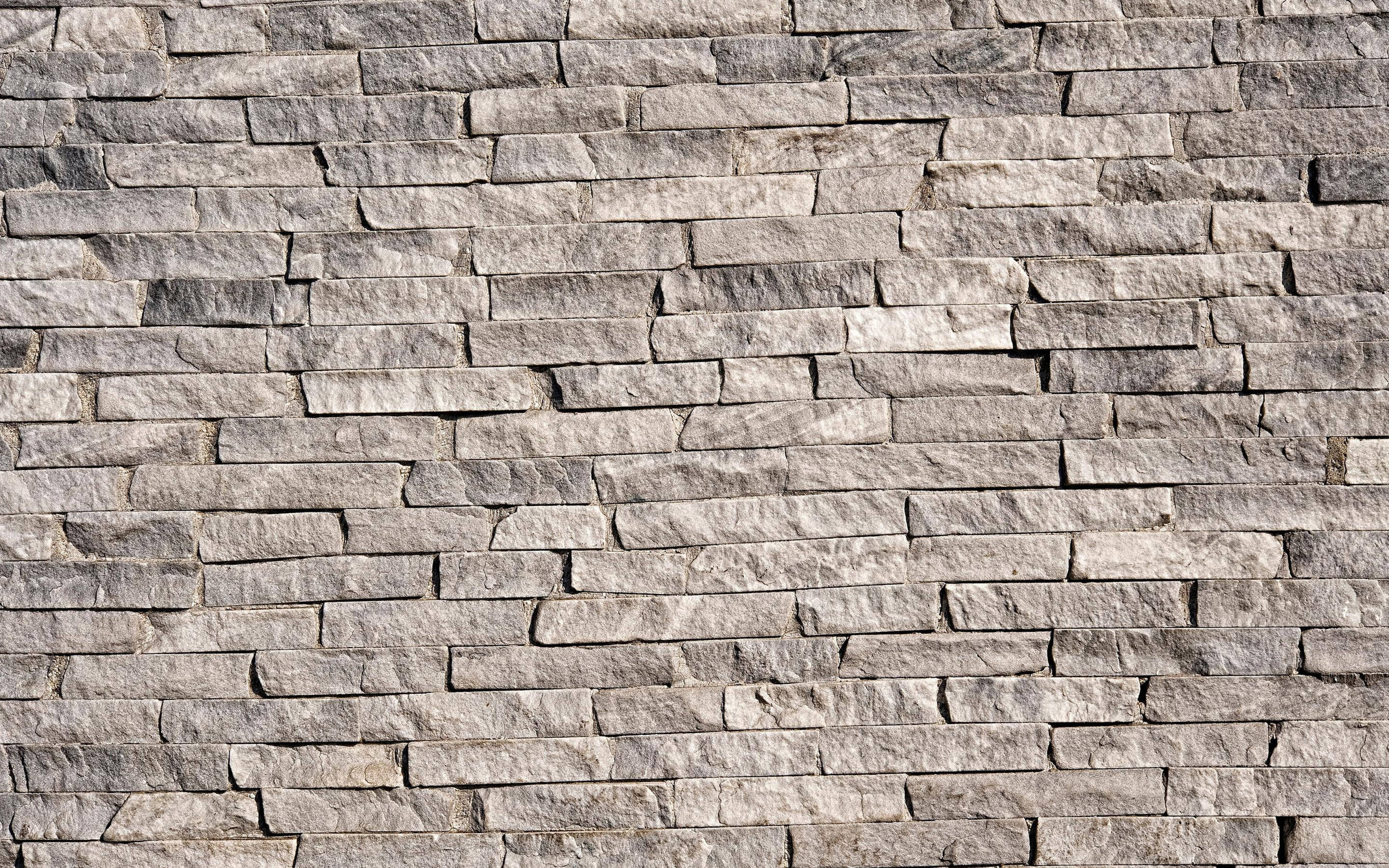 bare symmetrical stone wall cladding, textured gray stone wall, irregularly shaped blocks, 2K Desktop Wallpaper