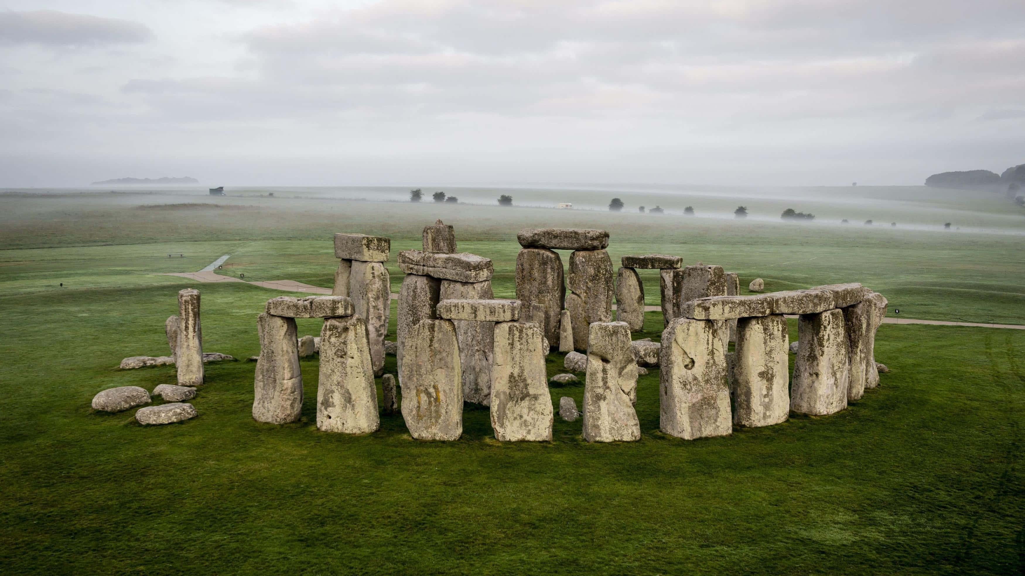 Stonehenge, misty green field, overcast sky, 2K Desktop Wallpaper