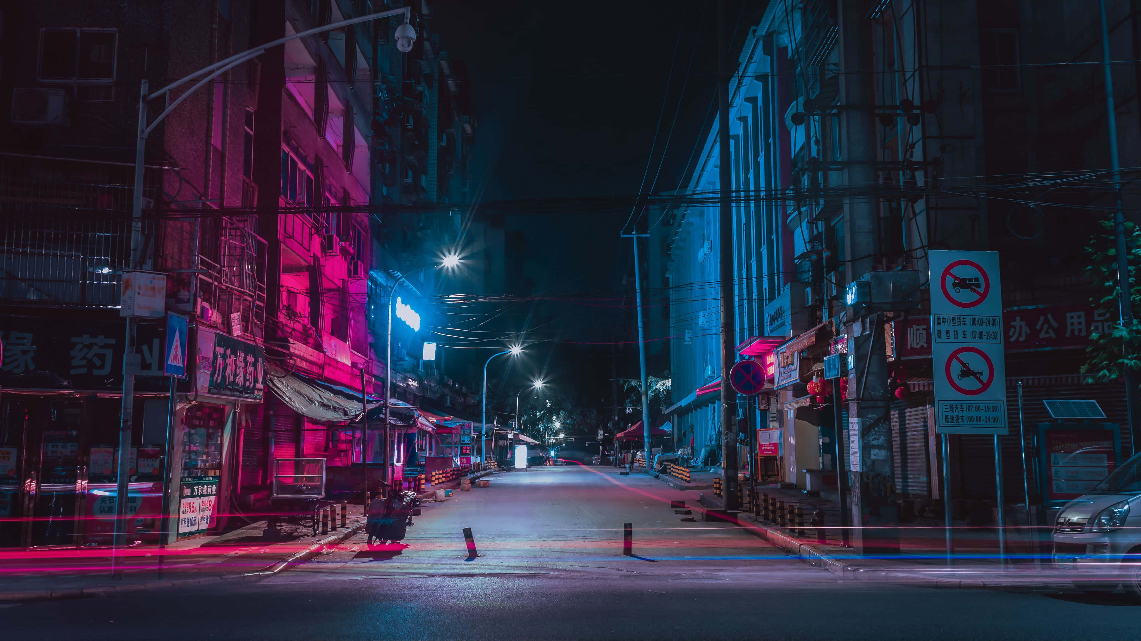 neon-drenched urban street, pink and blue lights, wet pavement, 4K Desktop Wallpaper