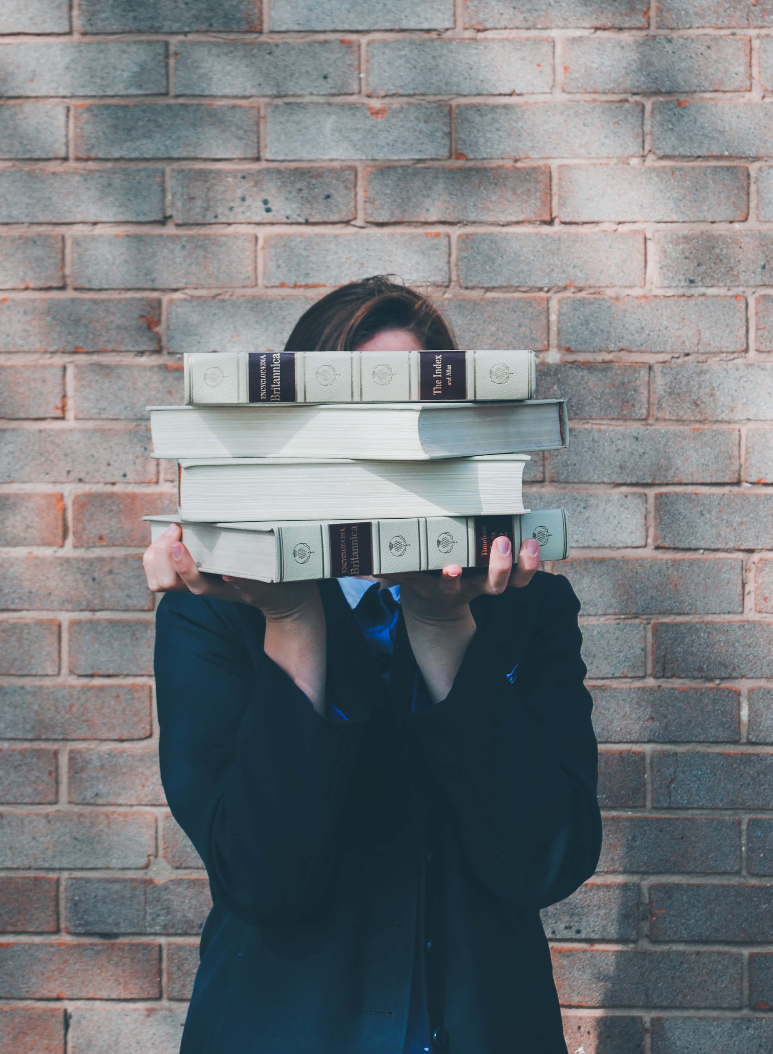 dark blazer, thick books, weathered brick wall, 2K Phone Wallpaper