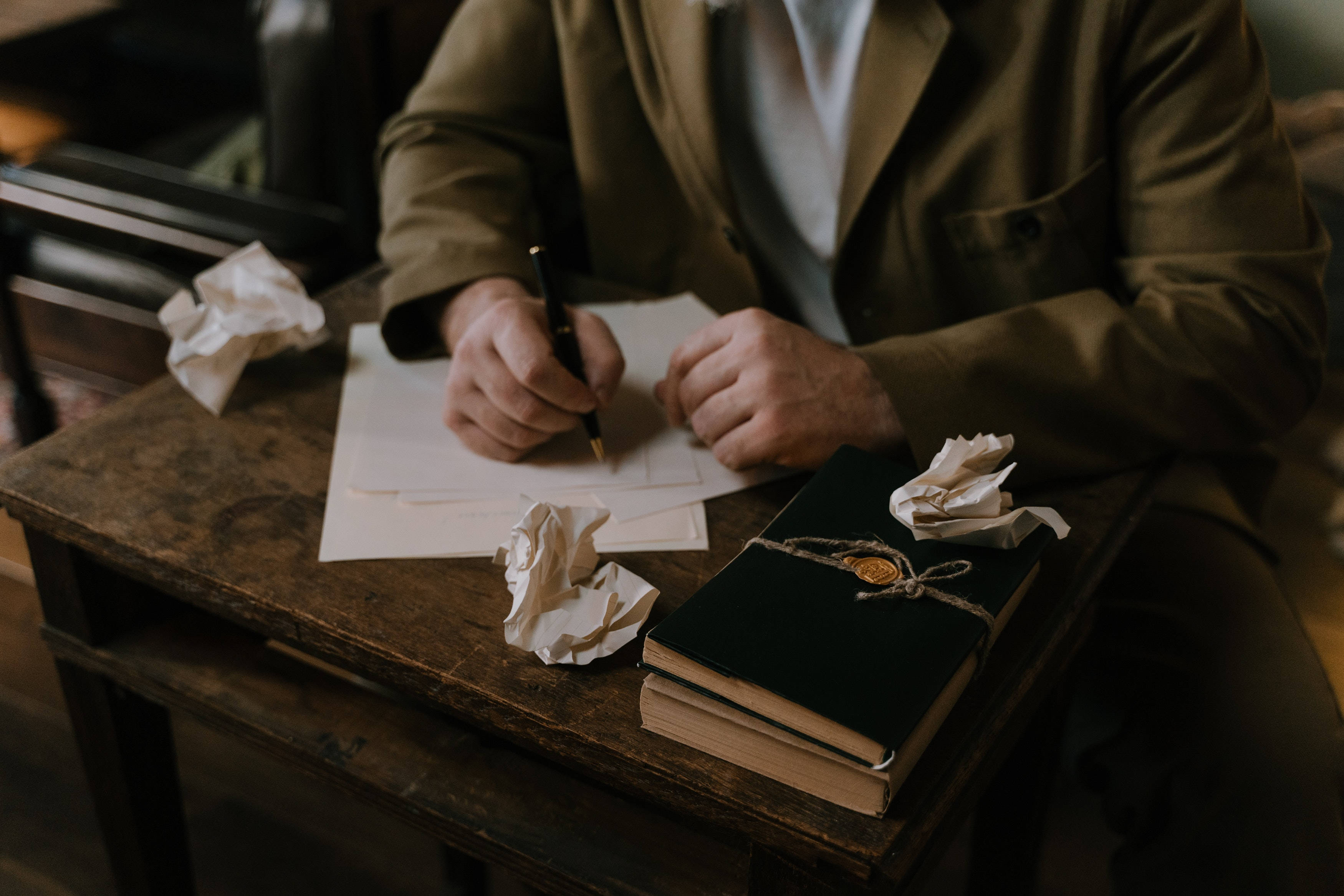 brown jacket, rustic wooden desk, crumpled drafts, 2K Desktop Wallpaper