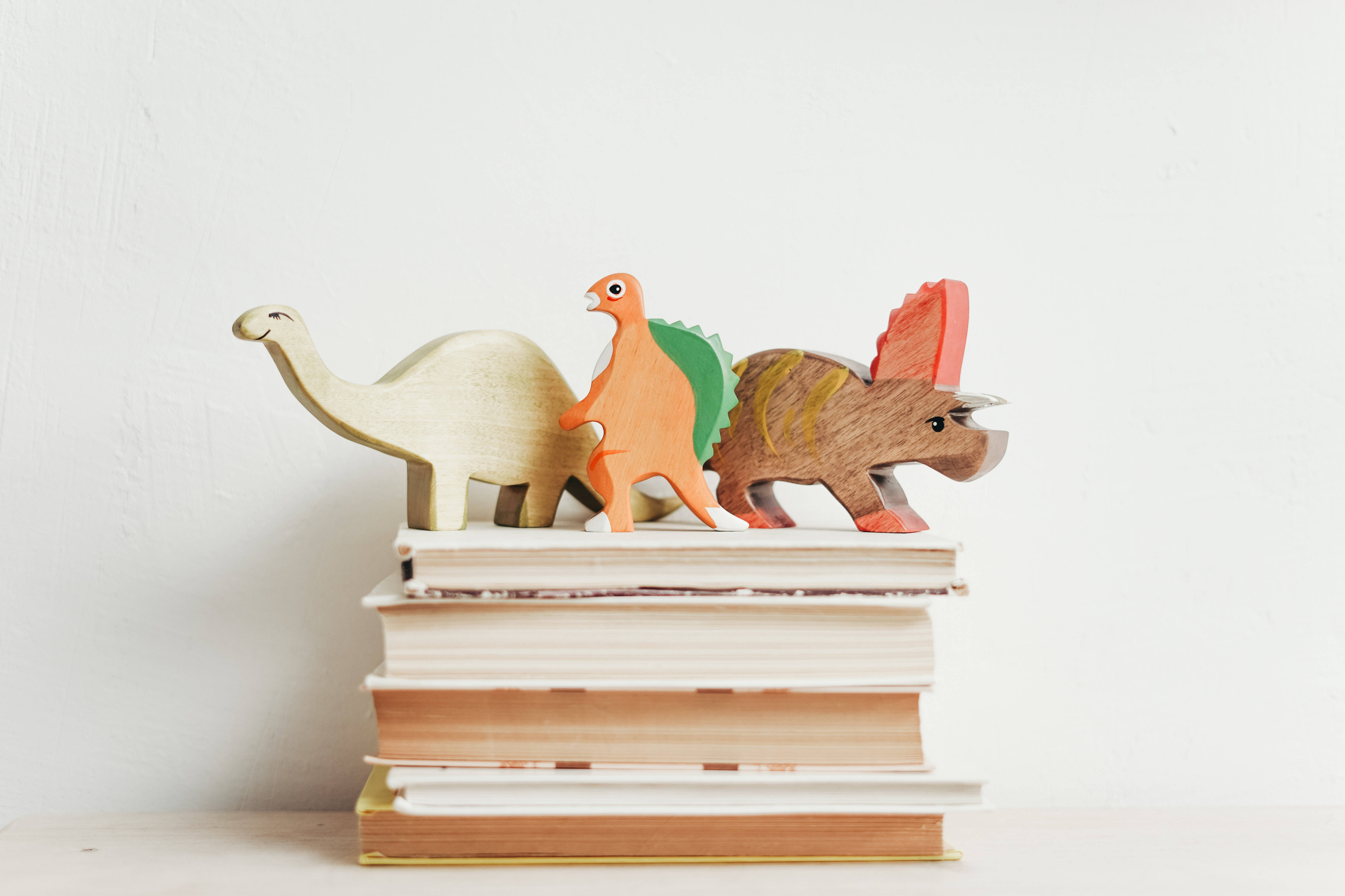 dinosaur figurines, wooden dinosaur figurines, stack of books, 5K Desktop Wallpaper