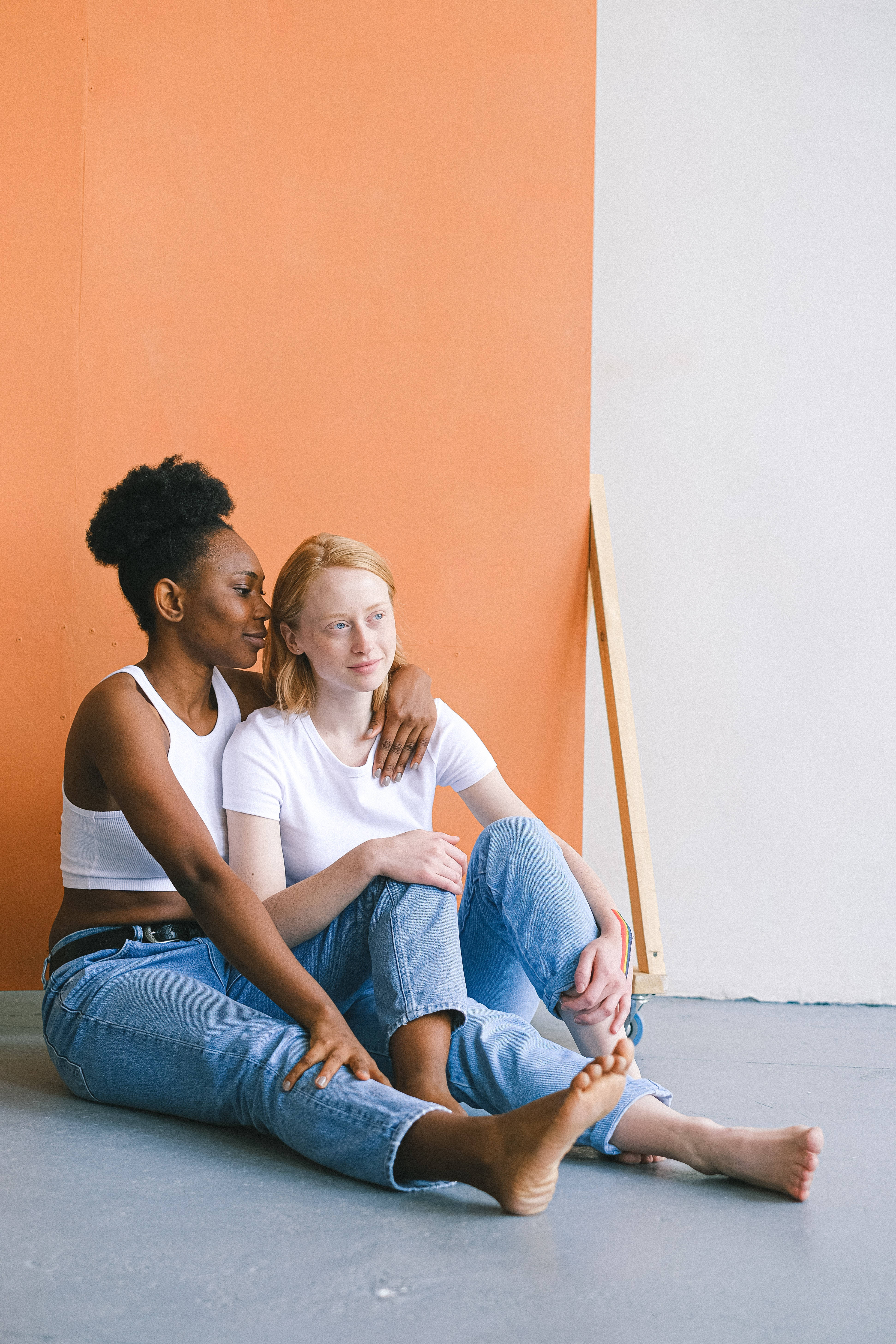 gray floor, orange and white wall, two women, 5K Phone Wallpaper